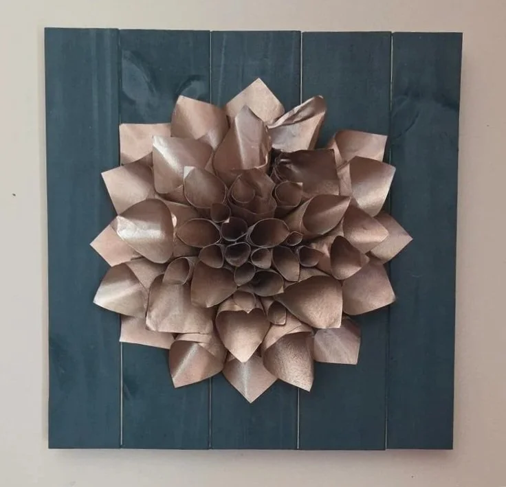 Close-up of a hand-crafted metal flower mounted on a square panel.