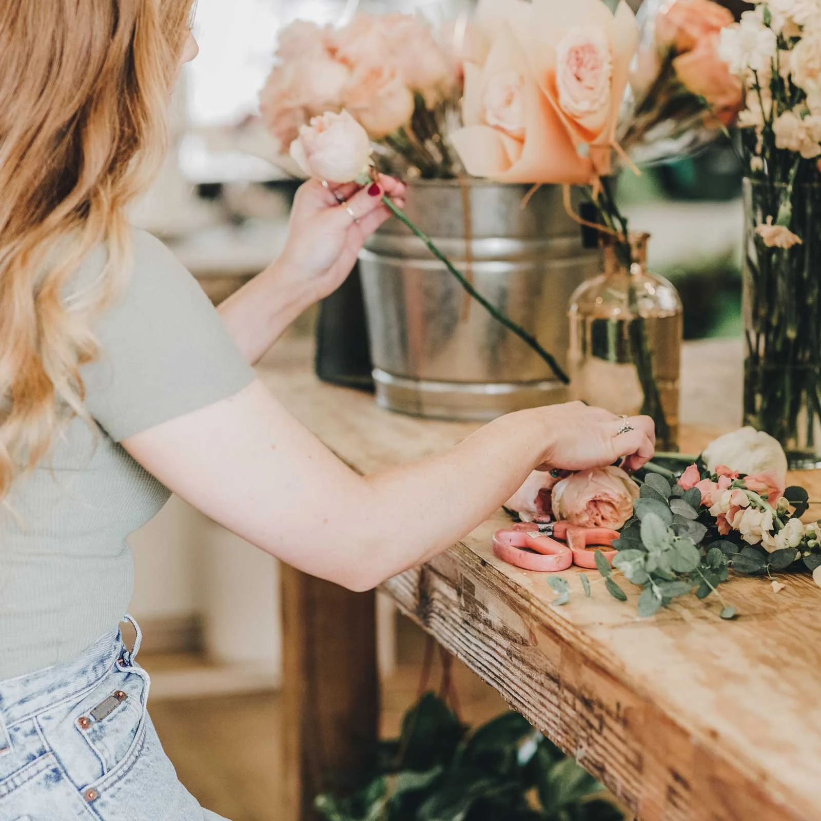 Maker arranging flowers at a worktable while building a creative small business