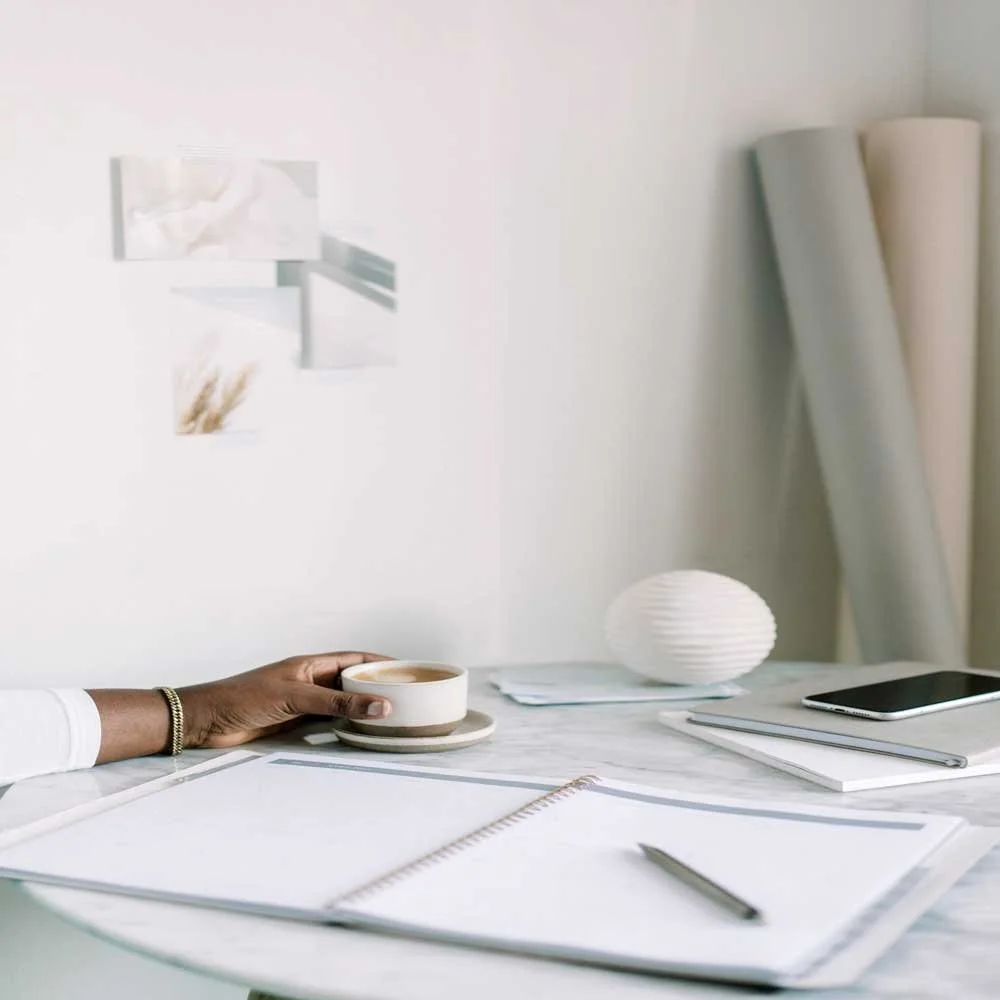 Creative workspace with notebook, tools, and coffee on a desk