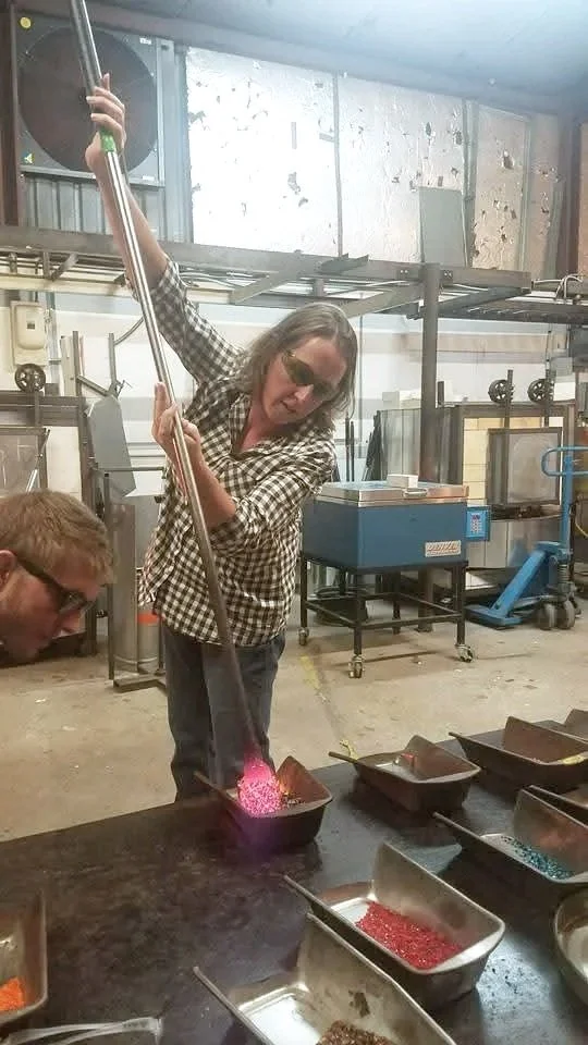 Christine Caldwell shaping molten glass in a glassblowing studio.