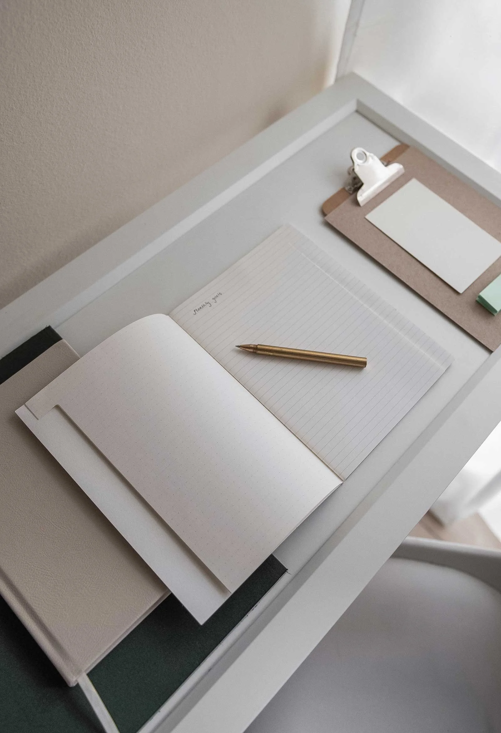 Minimal creative workspace with a notebook, pen, and planning materials, representing the need for structure and clarity in a growing creative business