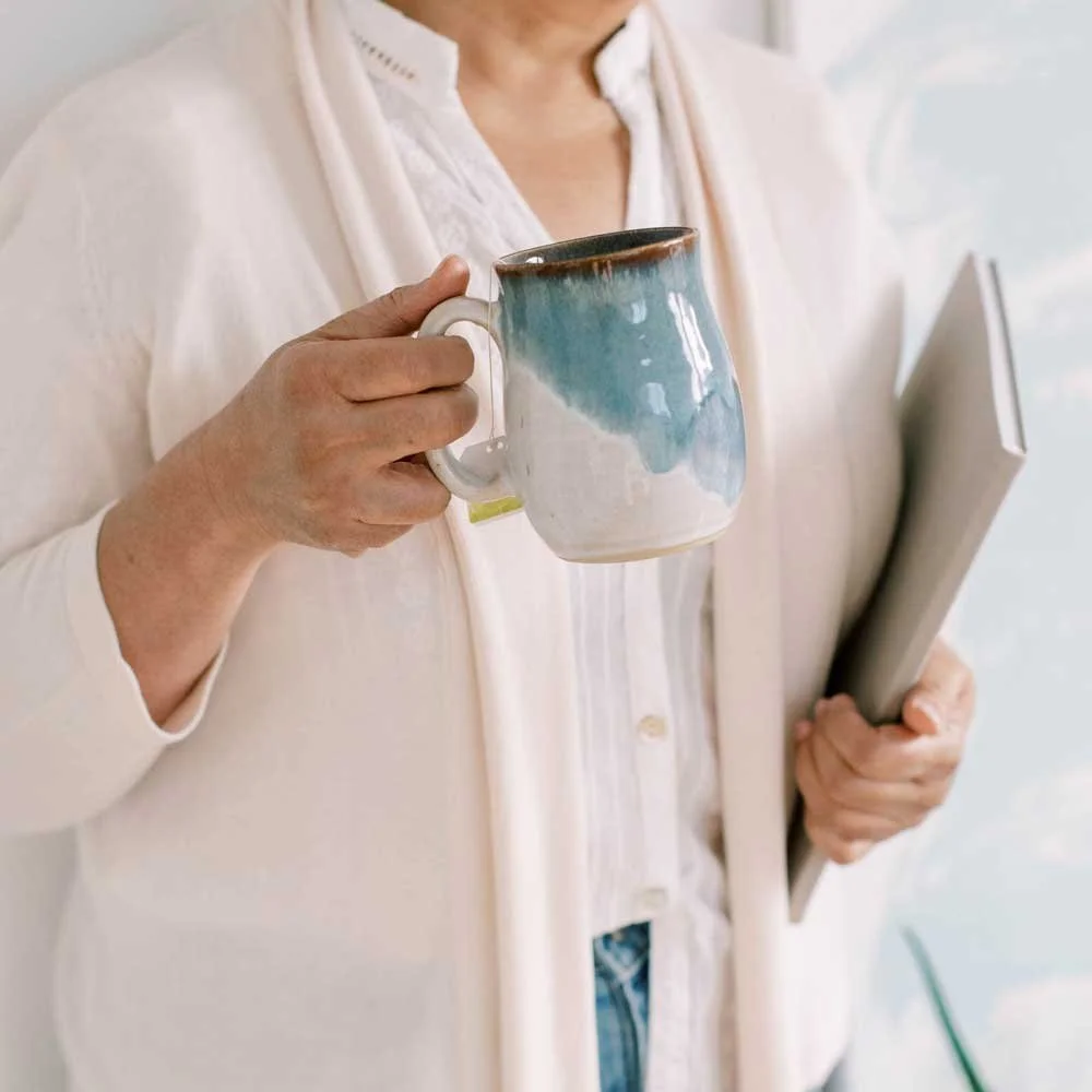 Person holding a mug in a creative workspace