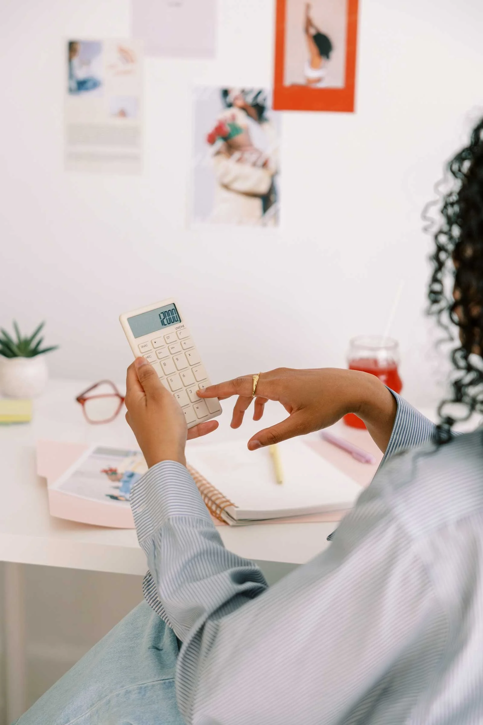 Hands using a calculator to review pricing, costs, and business numbers
