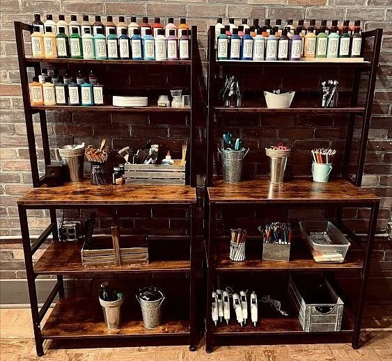 Wooden shelves stocked with paint and art supplies inside Studio 31·13.
