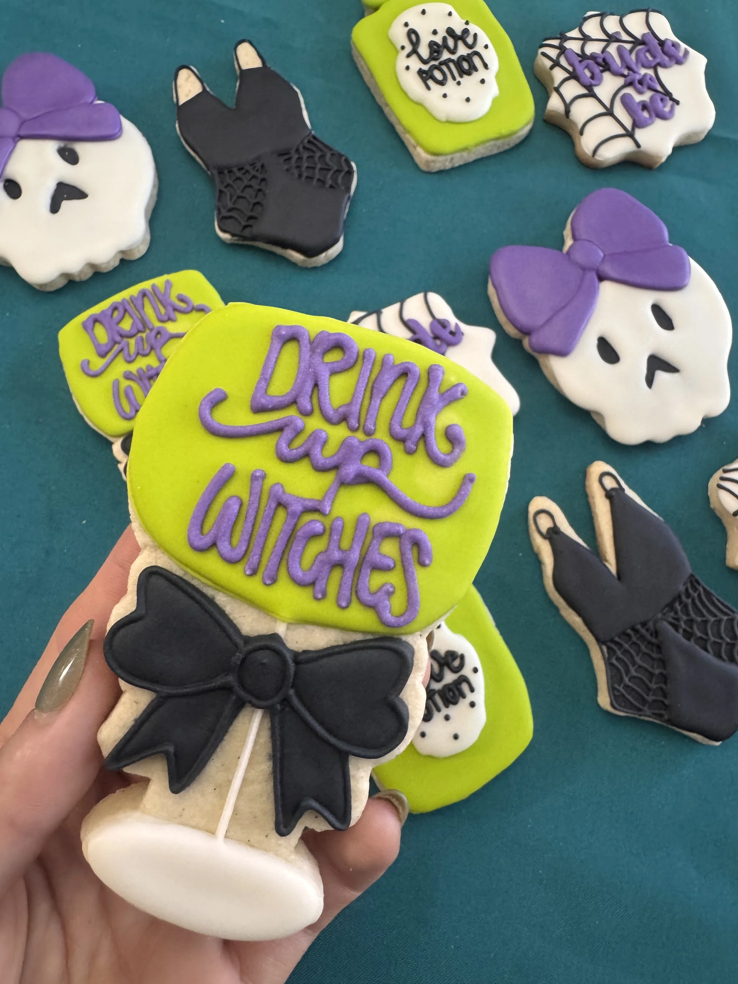 Halloween cookies decorated with skulls, bows, spider webs, and phrases like "Drink up witches" and "love mom" on some.