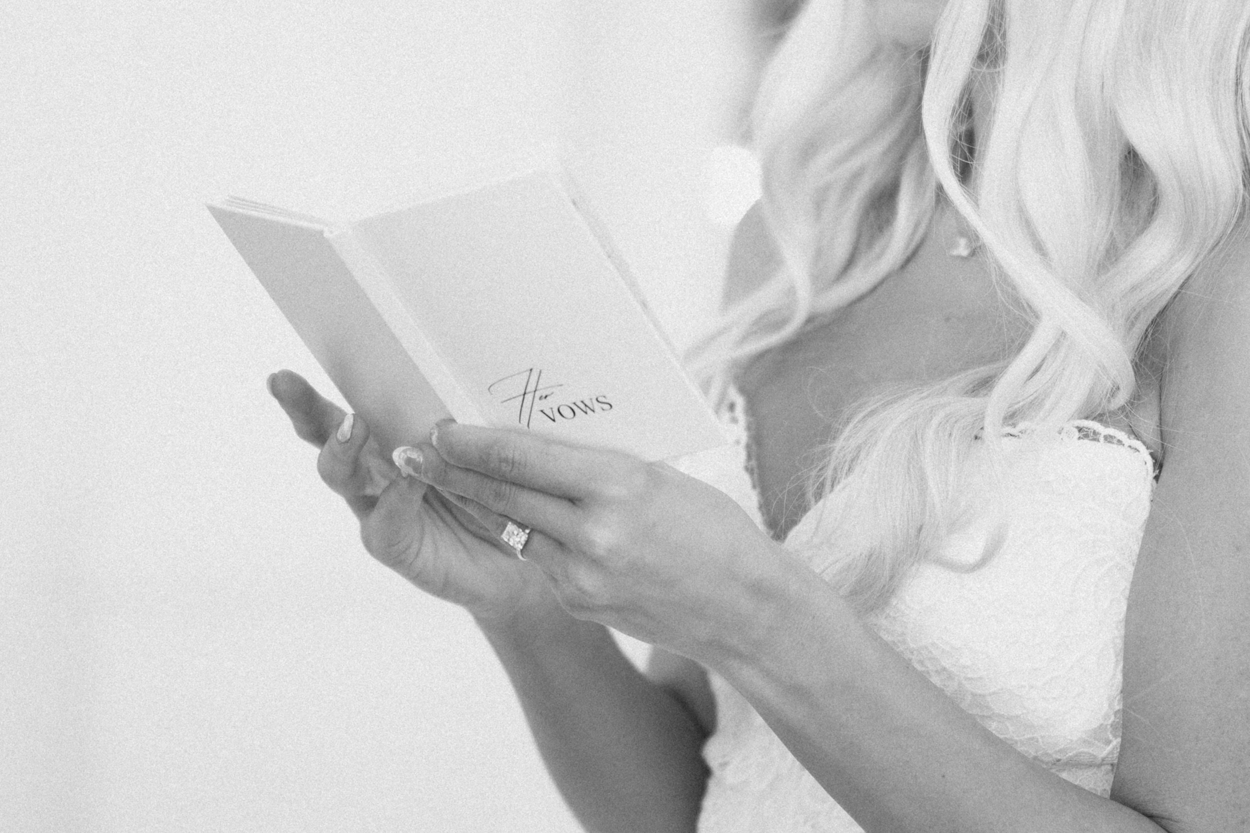A woman with blonde hair reading a book titled 'H vows'.