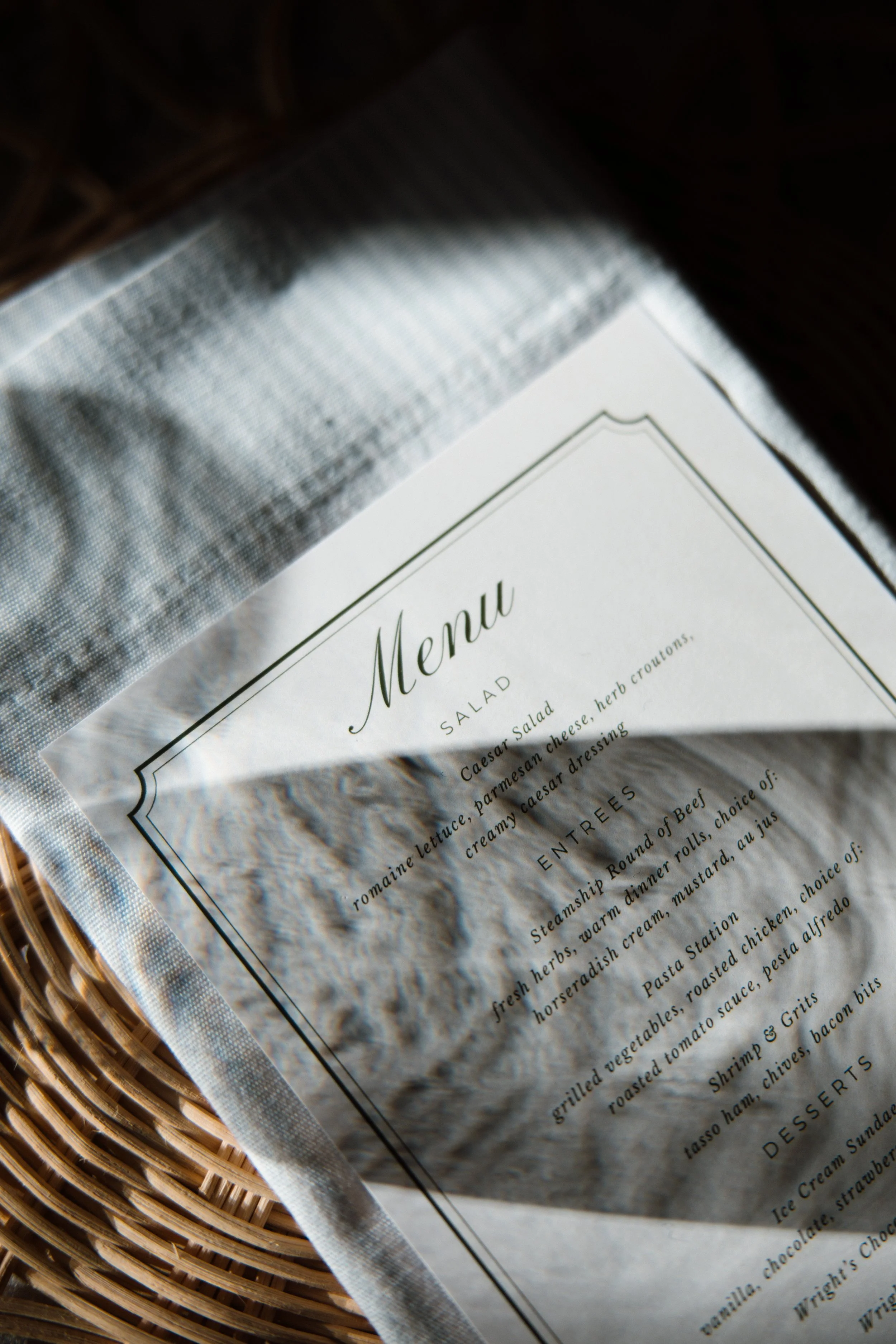 A close-up photograph of a restaurant menu placed on a woven rattan tray, with the menu partially visible and the word "Menu" in a large font at the top.