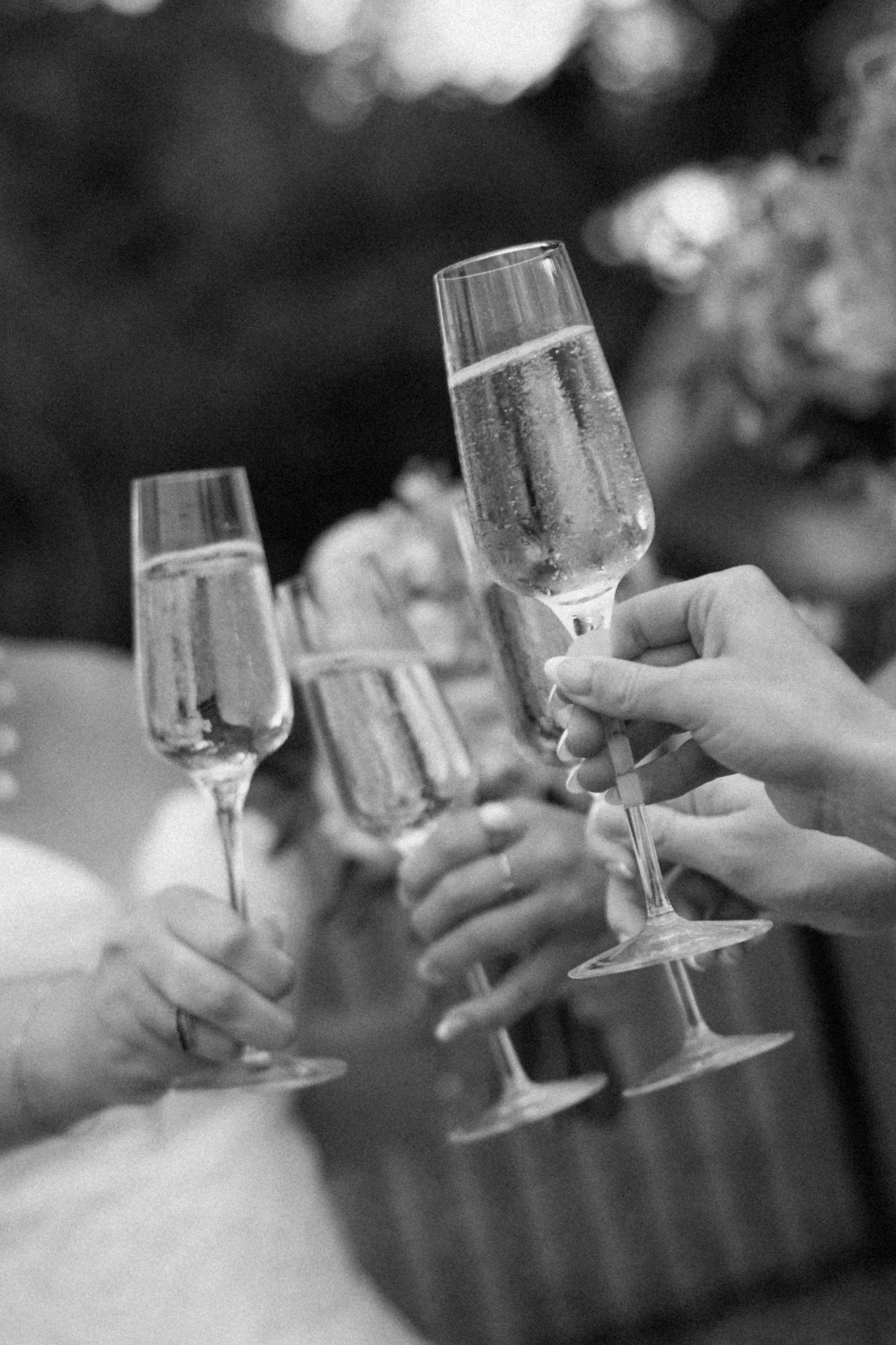 Close-up of multiple hands holding champagne glasses in a toast, with some glasses filled with sparkling liquid, in a celebratory setting.