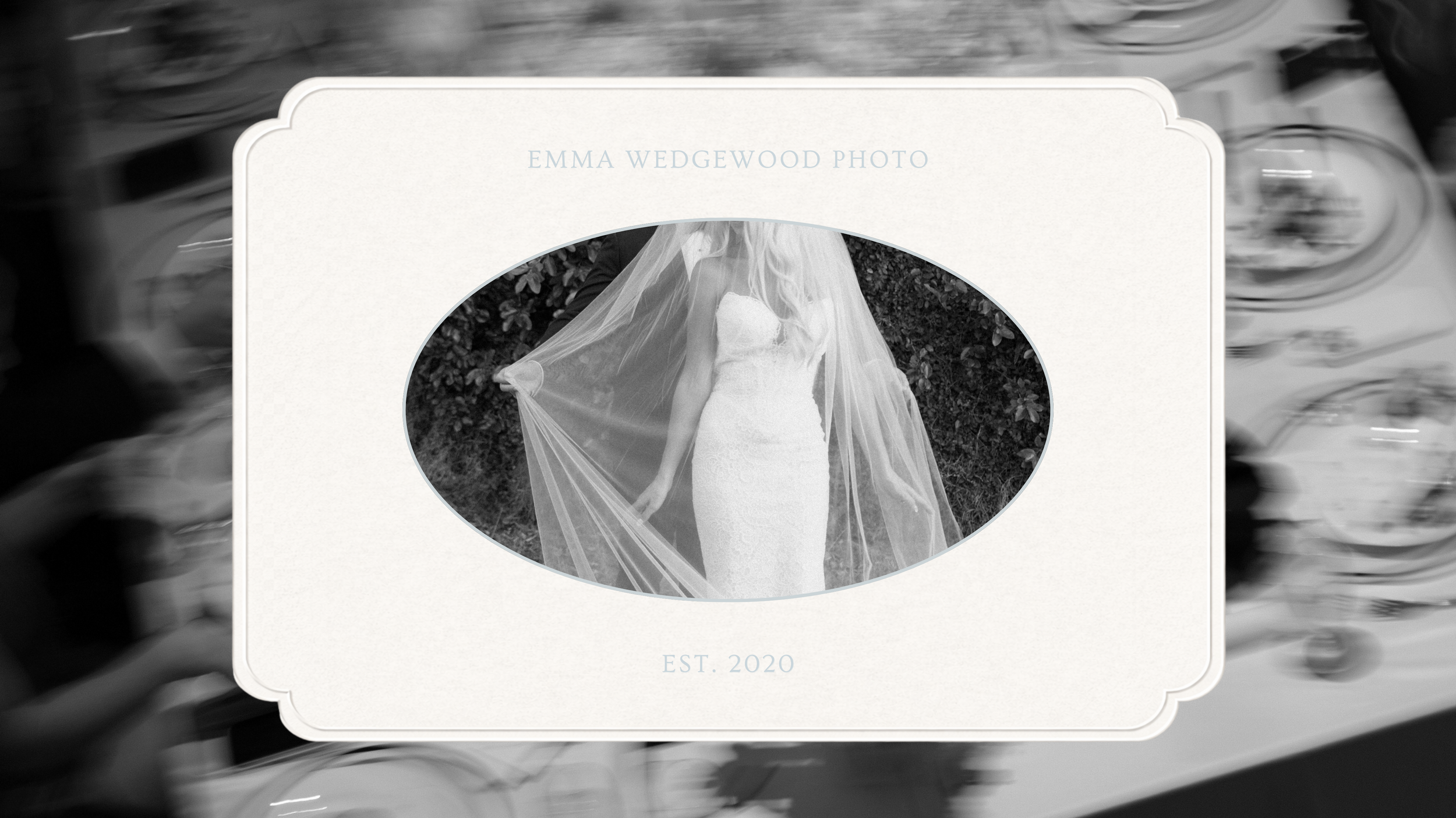 Black and white photo of a bride in a wedding dress holding a flowing veil, standing outdoors surrounded by foliage. The photo is framed inside an oval and has the text 'Emma Wedgewood Photo' and 'Est. 2020' at the top and bottom, respectively.