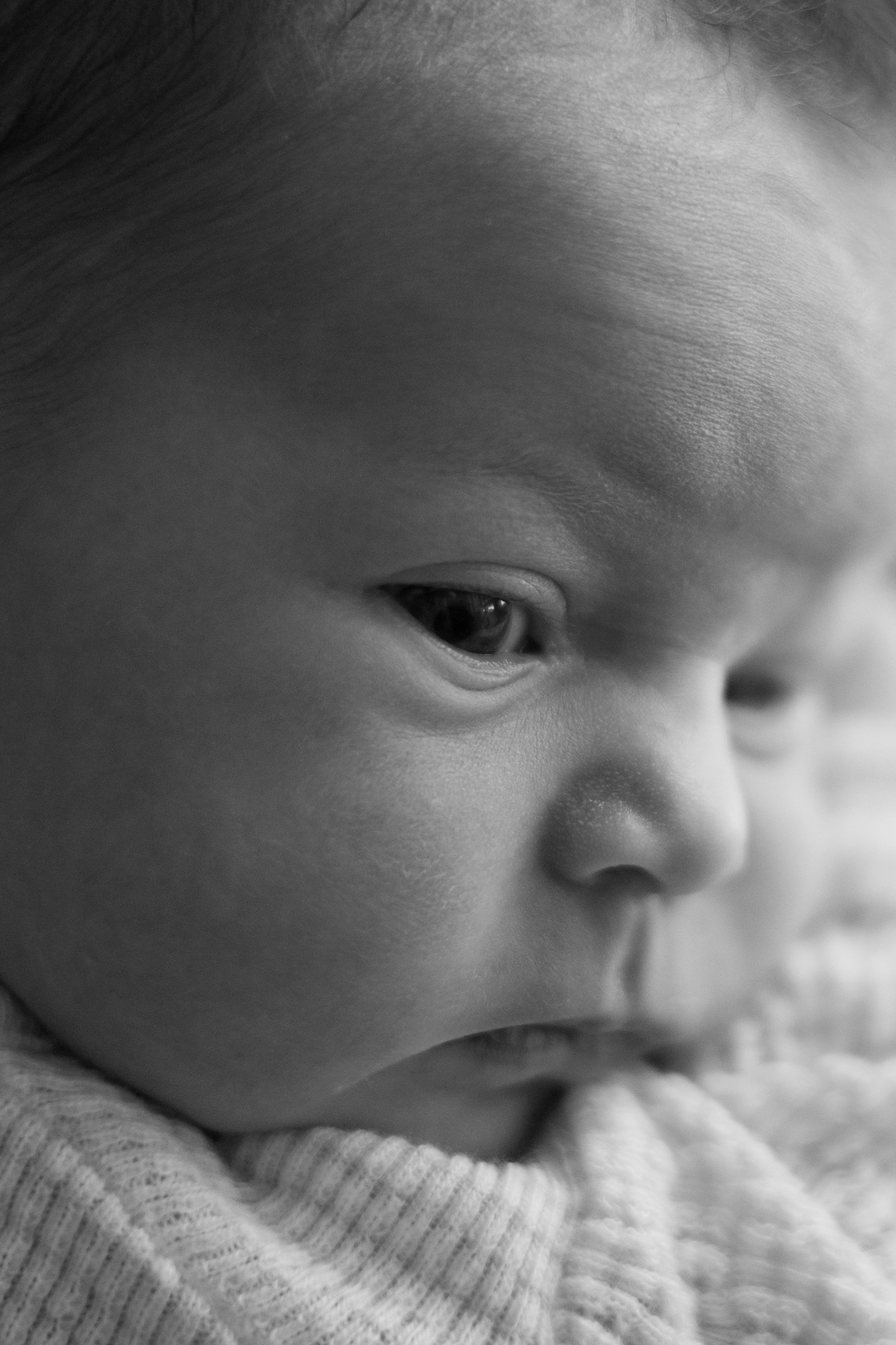 Close-up of a child's face, focusing on the eye and cheek in black and white.