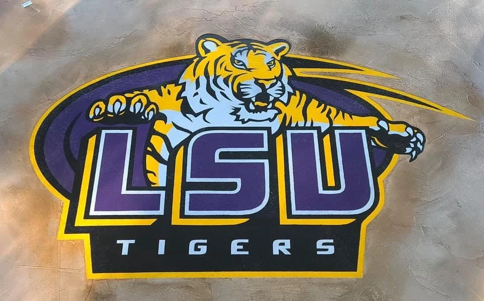 A covered outdoor patio with a stone fireplace and a patterned tile floor, opposite a garden area with steps and a man walking.