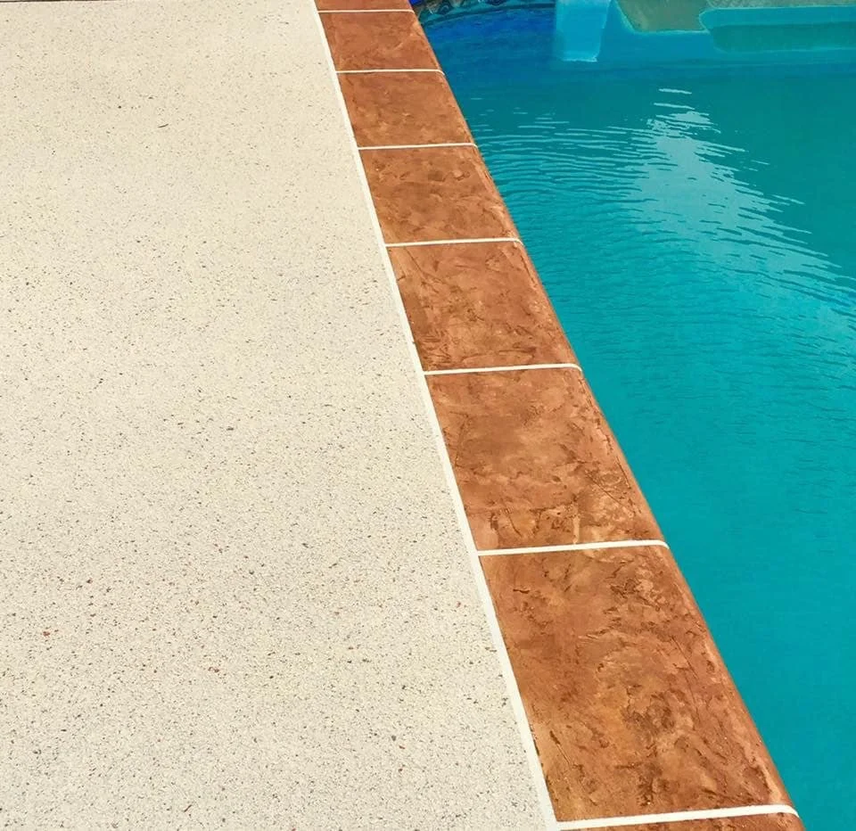 Close-up view of a swimming pool corner with beige concrete deck, orange ceramic tiles, and blue water.