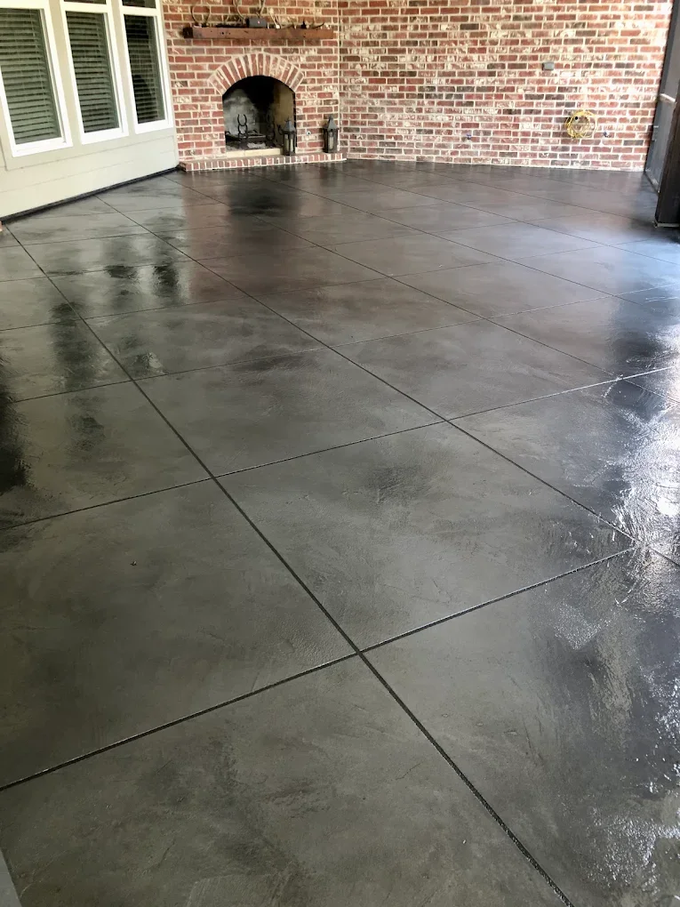 Charcoal stained concrete covered patio with scored tile pattern and brick fireplace by C&C Concrete Design