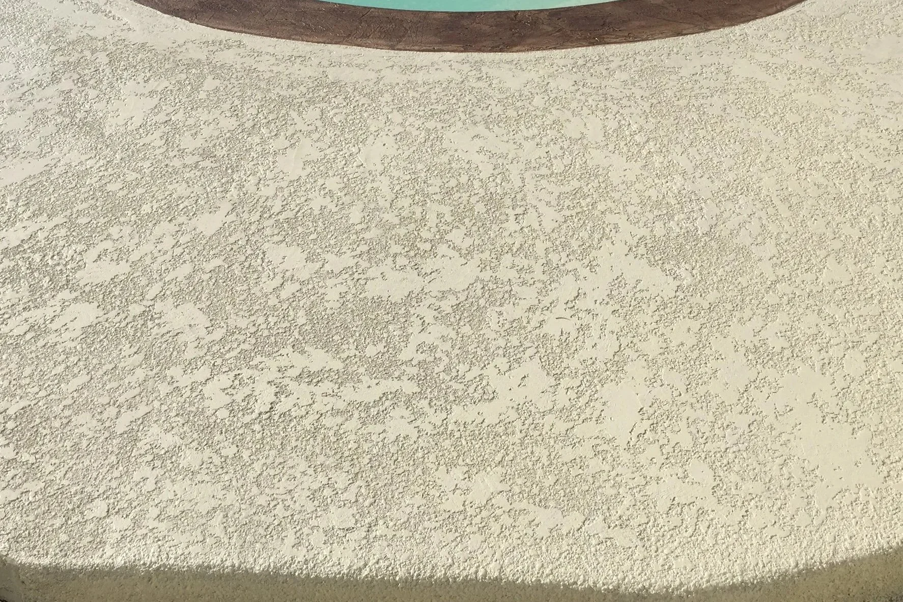 Close-up of knockdown texture concrete overlay on a pool deck with a stained coping border