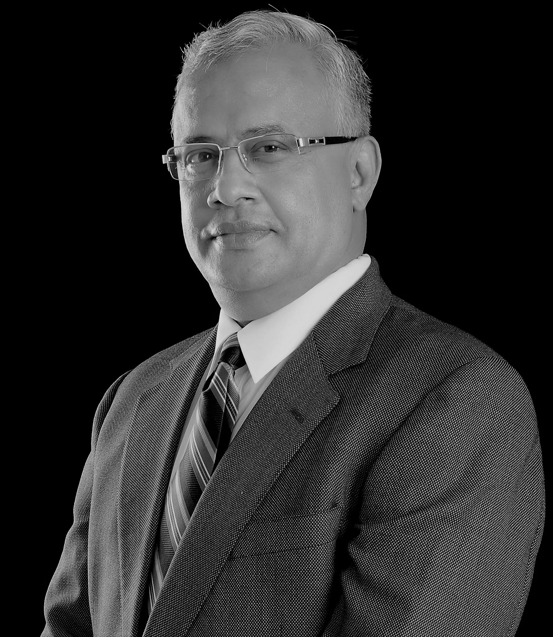 Black and white portrait of a middle-aged man in business attire wearing glasses, with short, light-colored hair, against a solid black background.