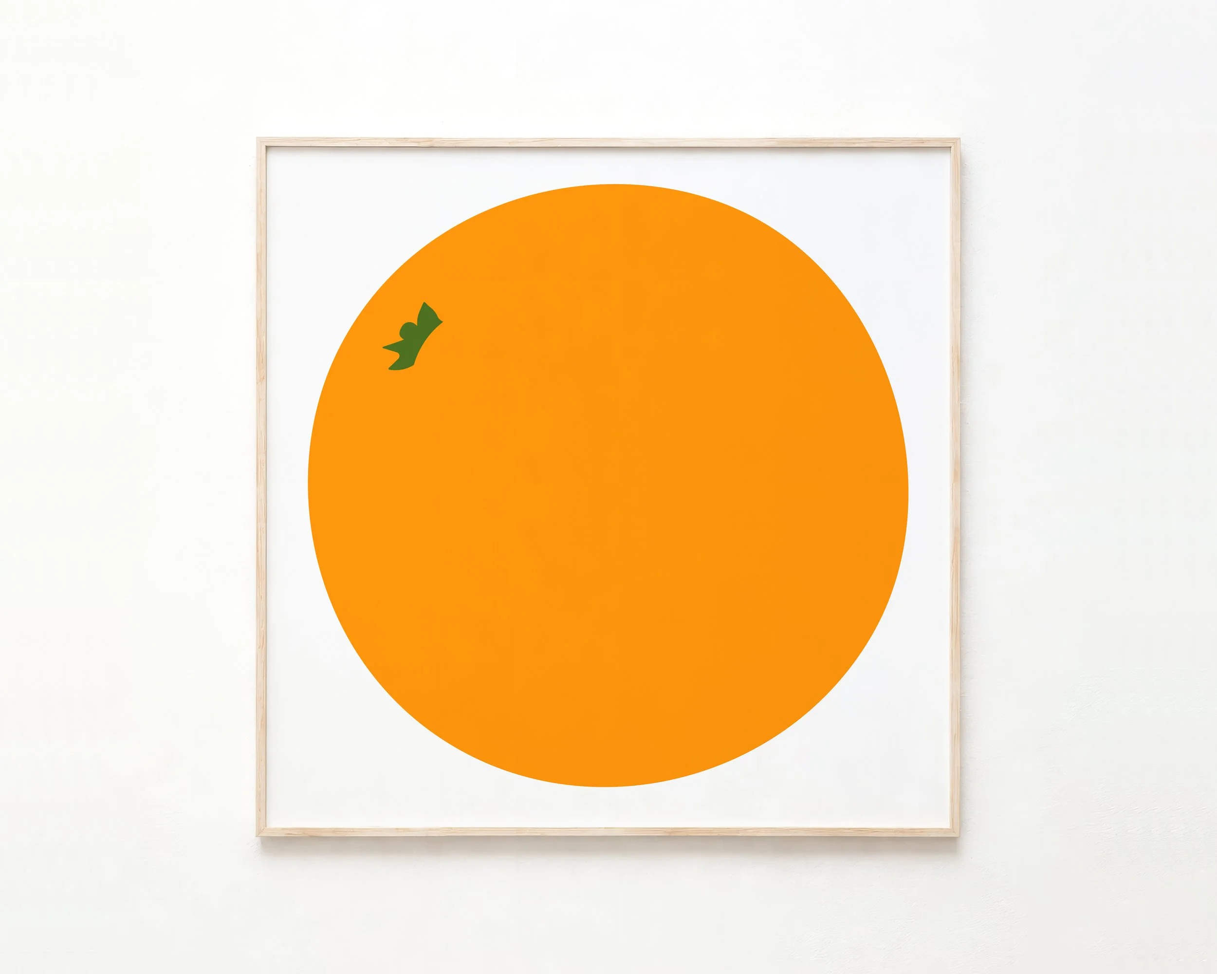 Minimalist art print of an orange semi-circle with a green leaf on top, framed and hung on a white wall.