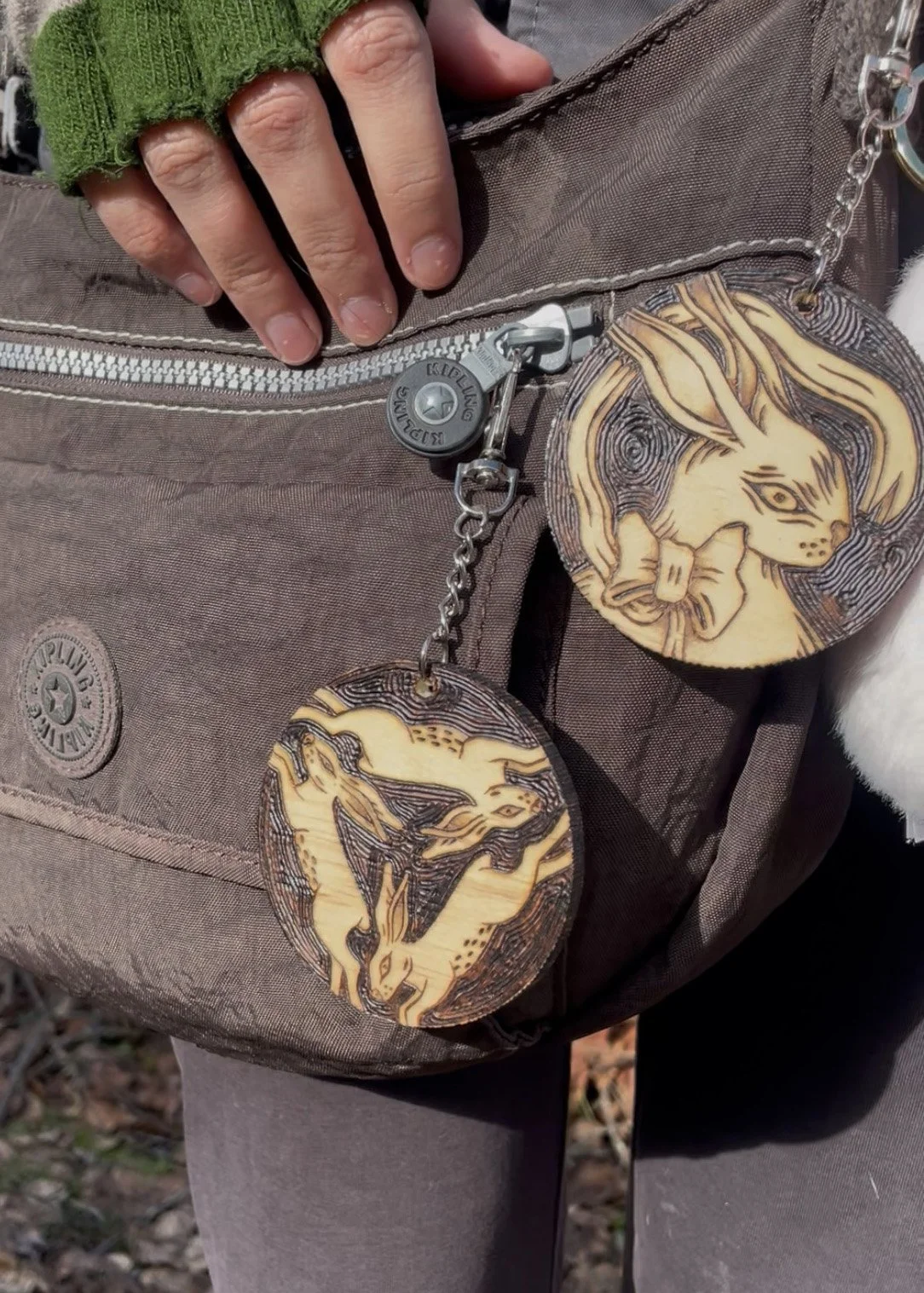 Amulette en bois ronde pyrogravée à la main représentant le symbole mystique et celtique des trois lapins connectés par les oreilles accroché à un sac.