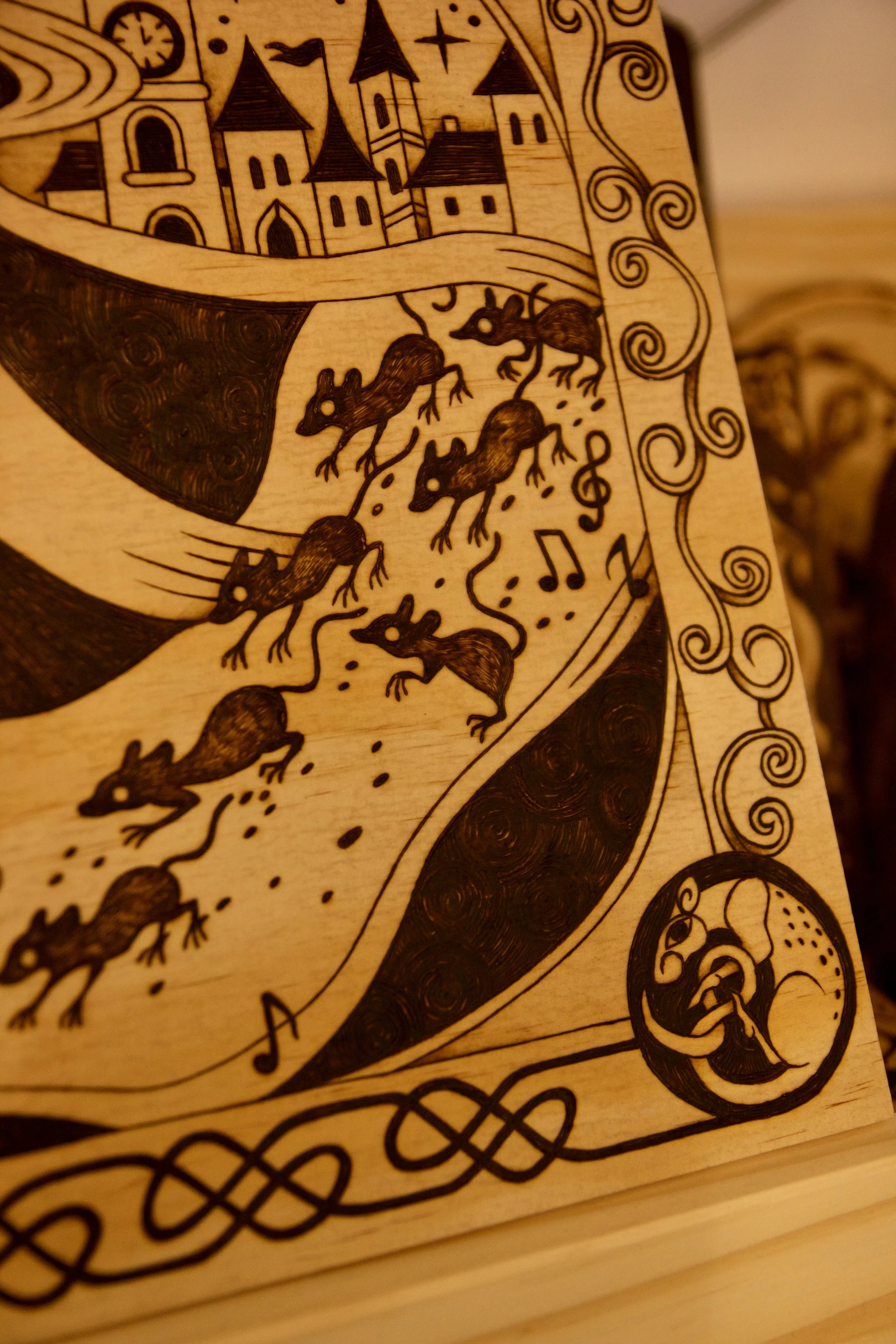 Zoom sur les rats - Grande pyrogravure carrée sur bois représentant le joueur de flûte de Hamelin guidant les rats, entourée d'entrelacs médiévaux.