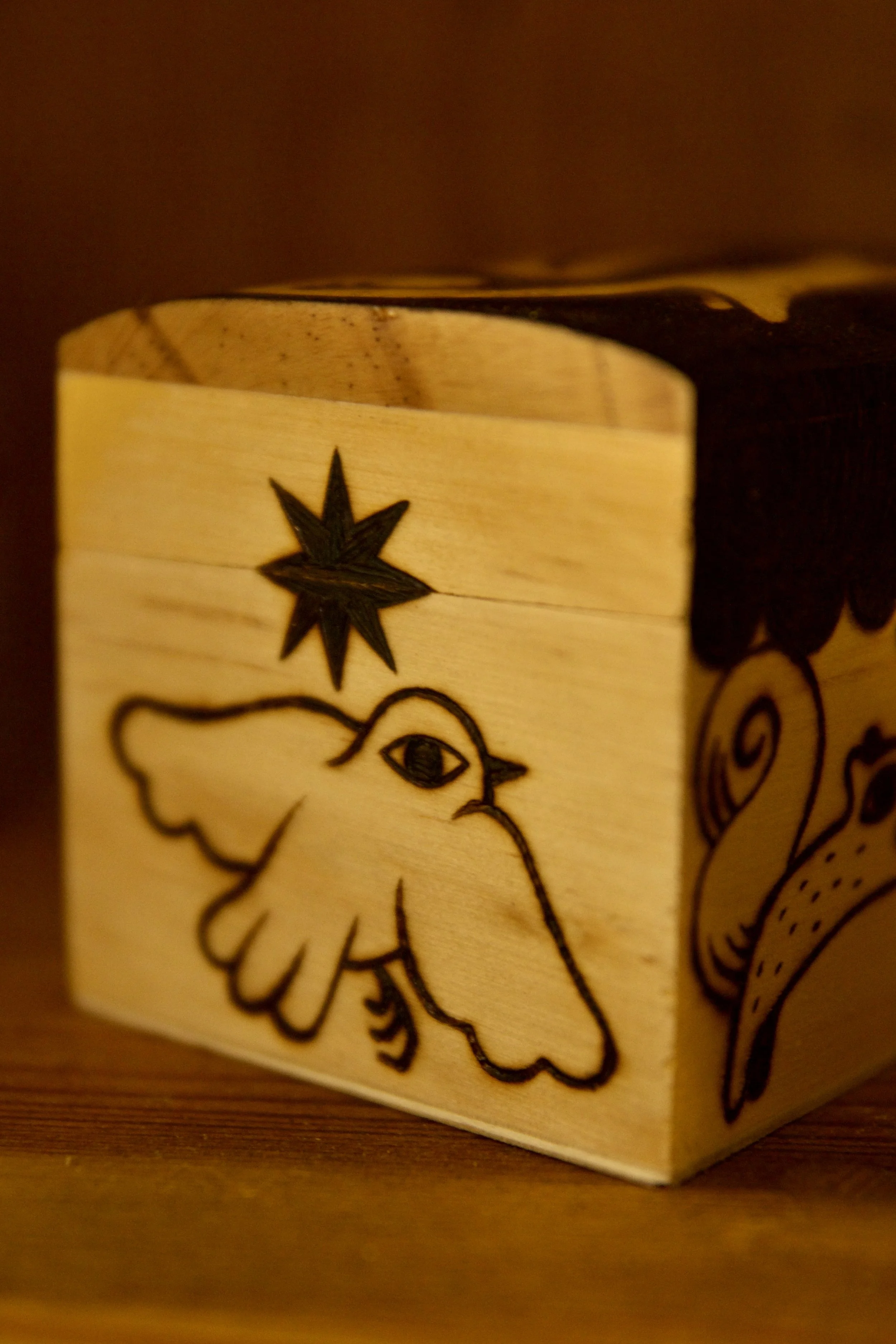 Zoom sur une petite boîte en bois mystique pyrogravée main, illustrée avec des écureuils, un renard, un oiseau et les phases de la lune.