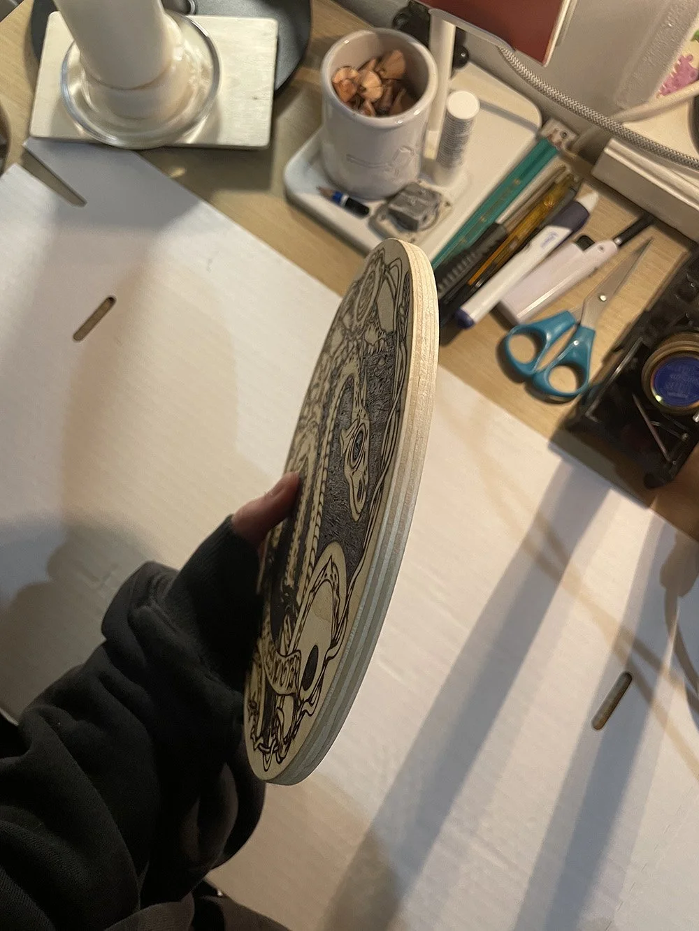 Vu de la tranche d'une pyrogravure artisanale ronde sur bois représentant la silhouette mystique du monstre du Loch Ness sous les eaux sombres d'Écosse.