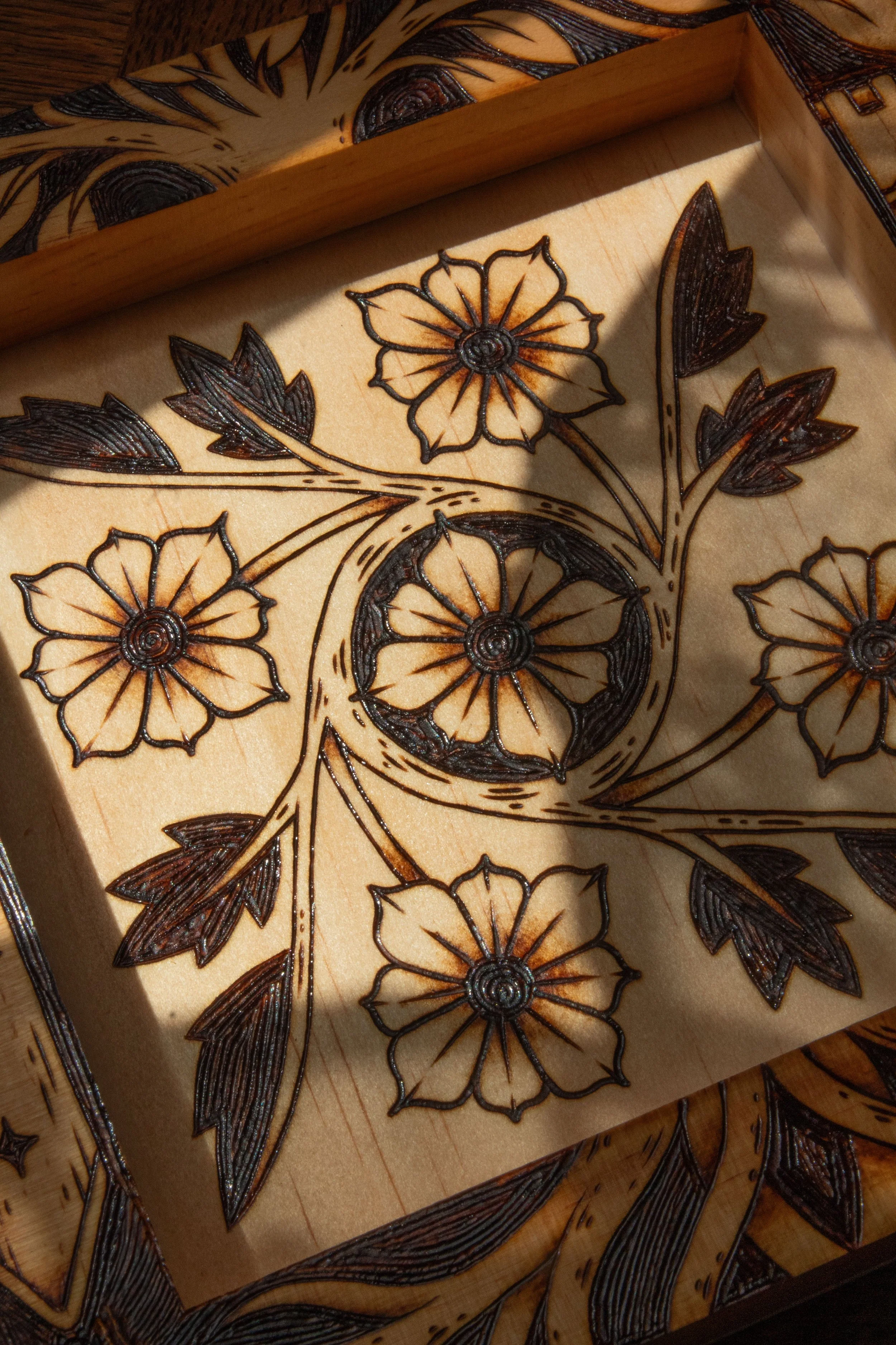 Plateau vide-poche carré en bois clair pyrogravé à la main avec des motifs de fleurs, d'entrelacs celtiques, d'un soleil et d'un croissant de lune mystique.