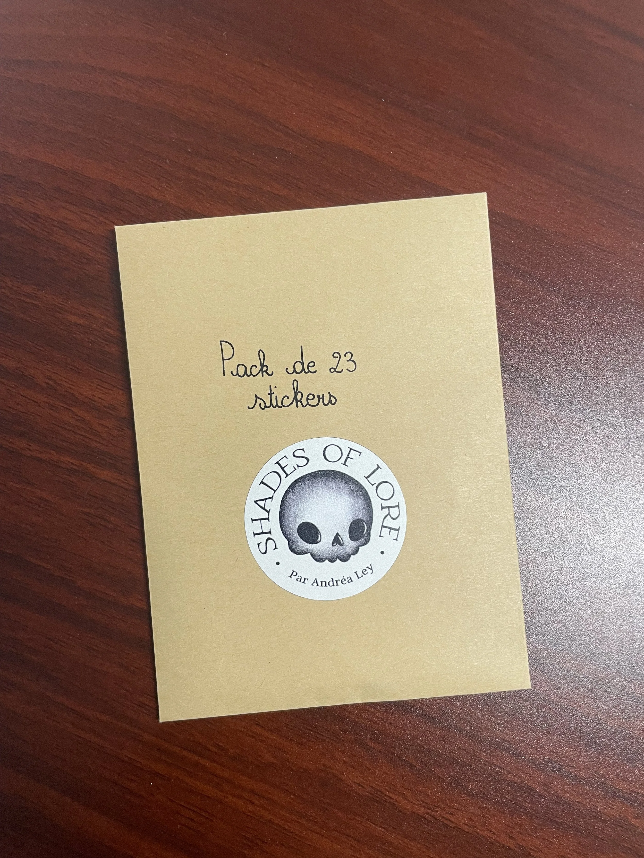Pack de 23 stickers  illustrés brillants aux tons chauds de bois, représentant des animaux de la forêt et des symboles mystiques inspirés de pyrogravures, dans un sachet avec logo.