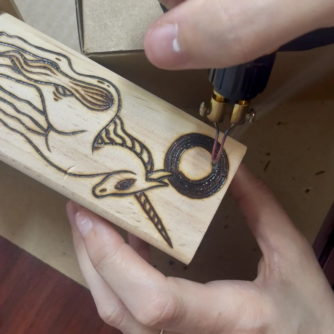 Une personne utilisant un outil de gravure laser pour décorer un morceau de bois avec une image d'une licorne.