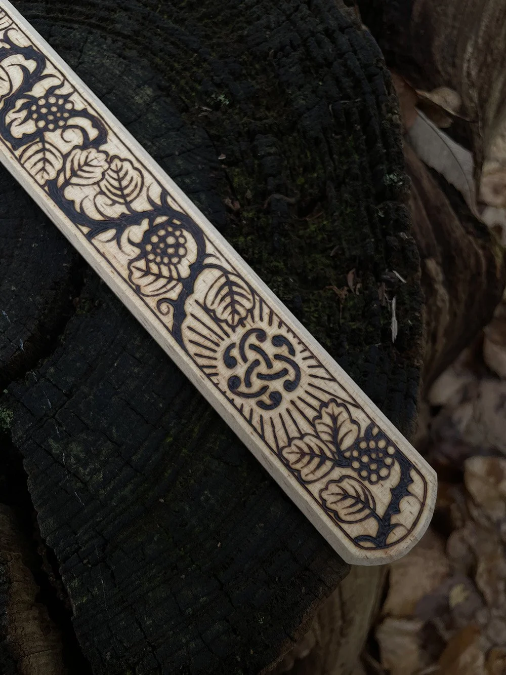 Zoom sur une épée décorative en bois clair entièrement pyrogravée à la main avec des motifs d'entrelacs celtiques, nœuds mystiques et inspirations médiévales.