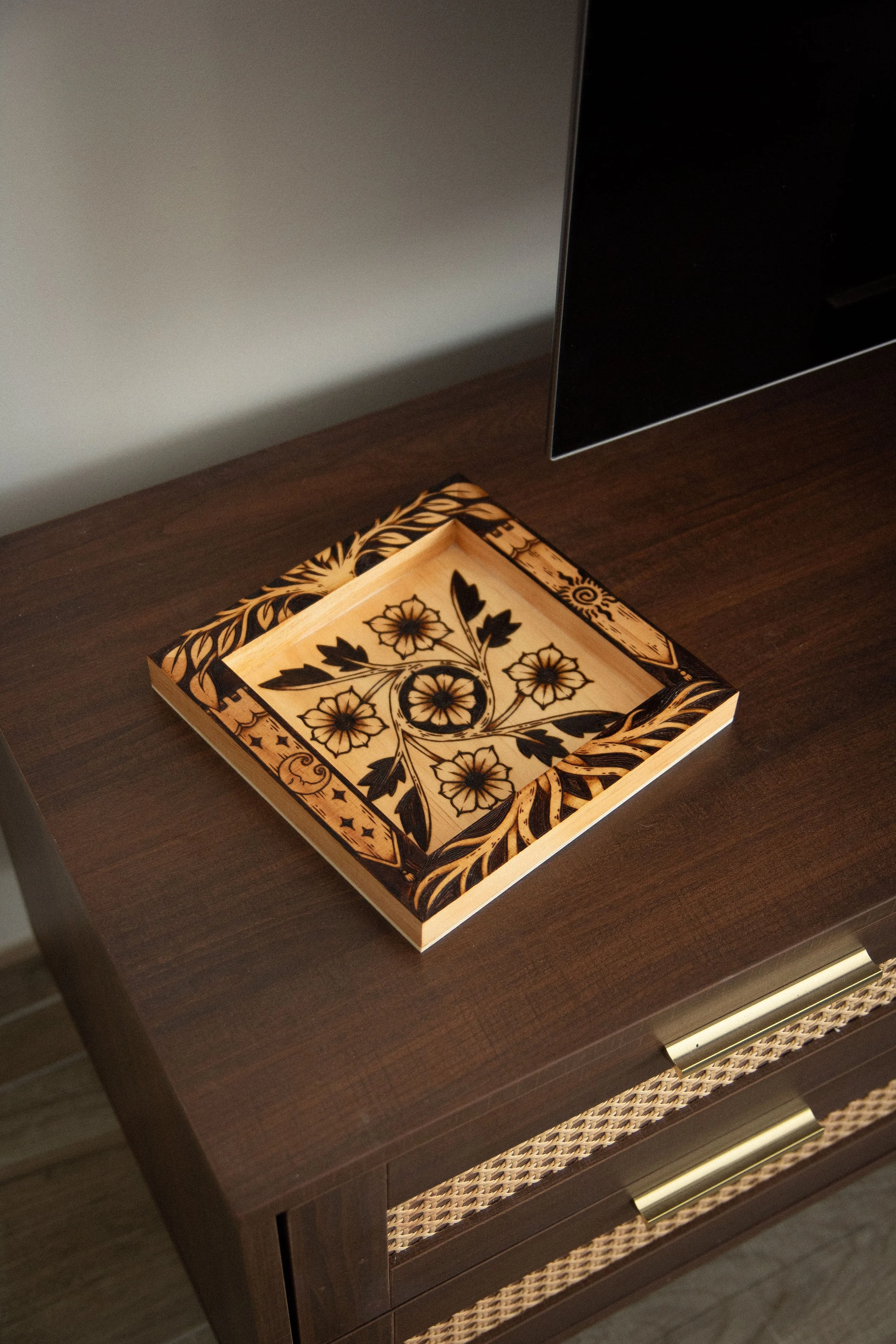 Plateau vide-poche carré en bois clair pyrogravé à la main avec des motifs de fleurs, d'entrelacs celtiques, d'un soleil et d'un croissant de lune mystique.