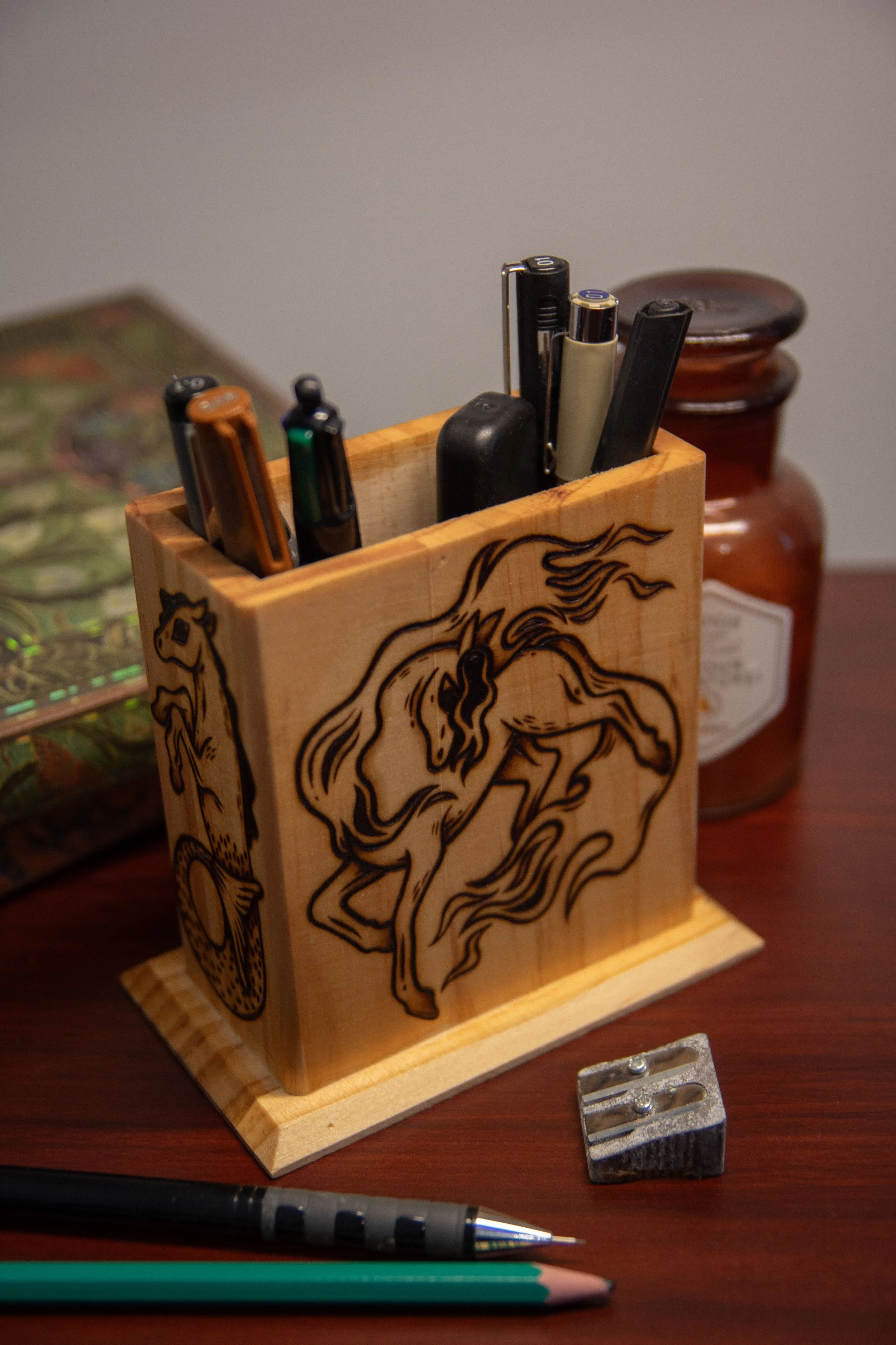 Face arrière d'un pot à crayons carré en bois artisanal, montrant une face pyrogravée avec soin représentant un cheval de feu magique.