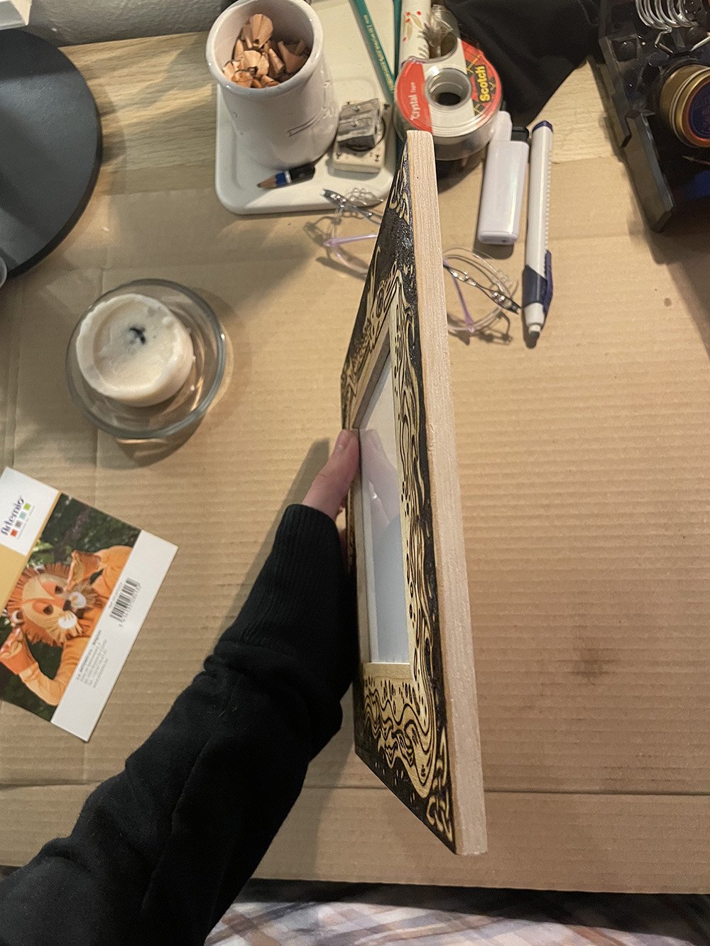 Vue de la tranche d'un cadre photo en bois artisanal avec un dragon pyrogravé à la main dans un style médiéval et fantastique.