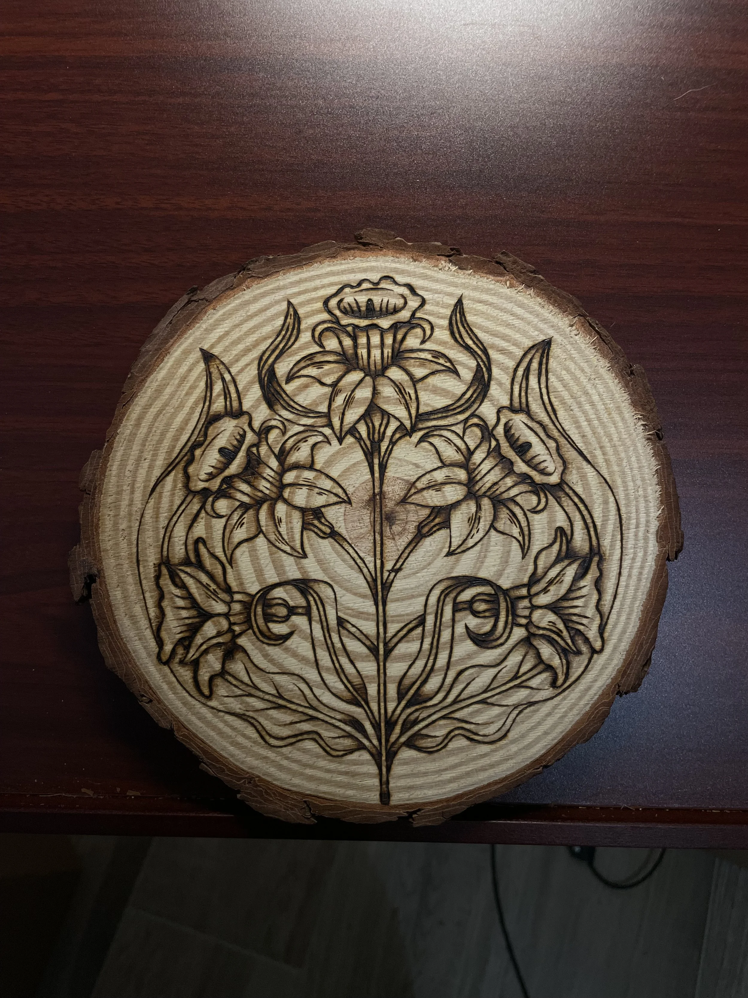 Plaque en bois brut avec des motifs naturels, pyrogravée à la main avec une illustration de jonquilles, fleurs du printemps et symbole de renouveau dans un atelier d'artisanat.