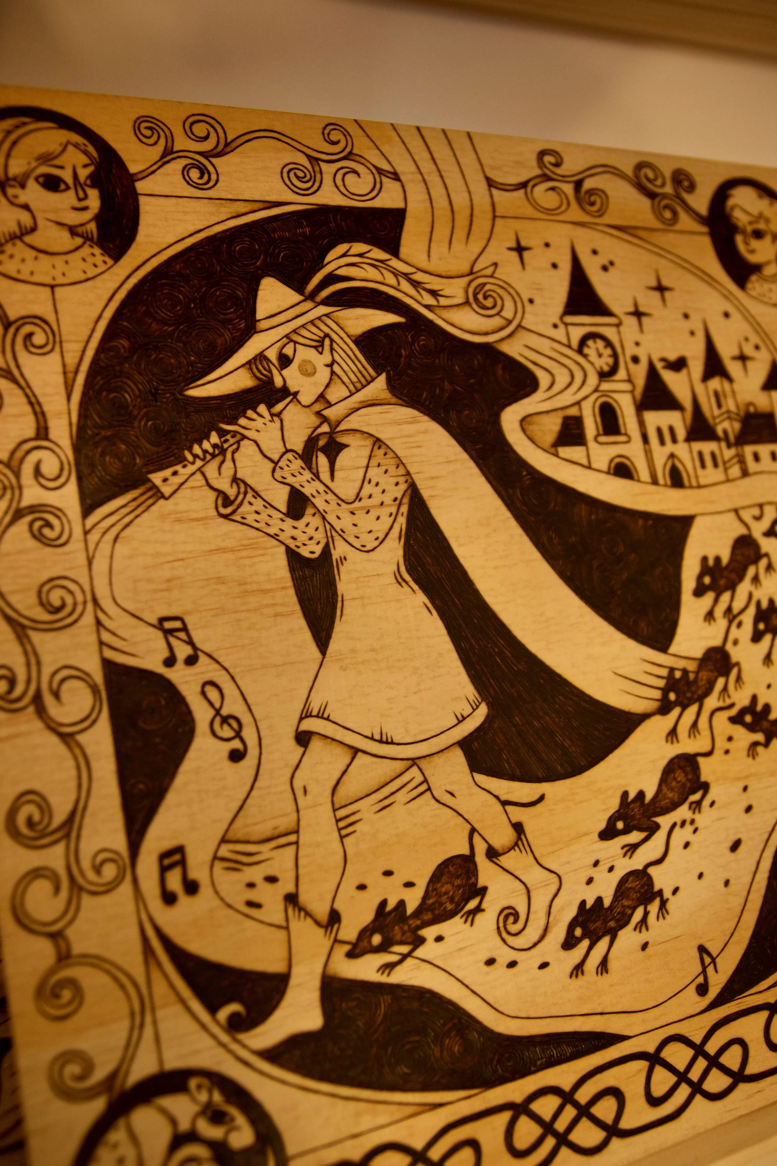Grande pyrogravure carrée sur bois représentant le joueur de flûte de Hamelin guidant les rats, entourée d'entrelacs médiévaux.