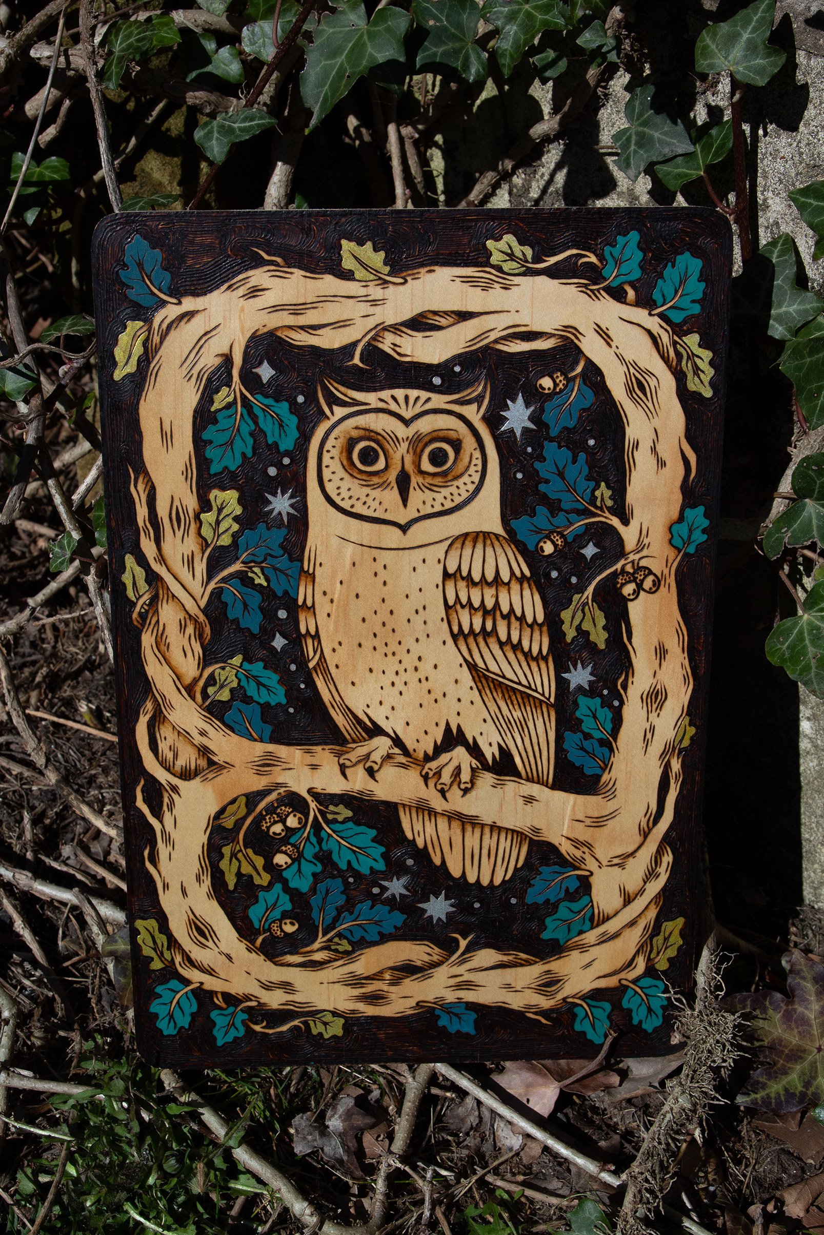Plaque décorative en bois gravée à la main représentant un hibou mystique, avec de délicats détails colorés à la peinture acrylique vu de face.