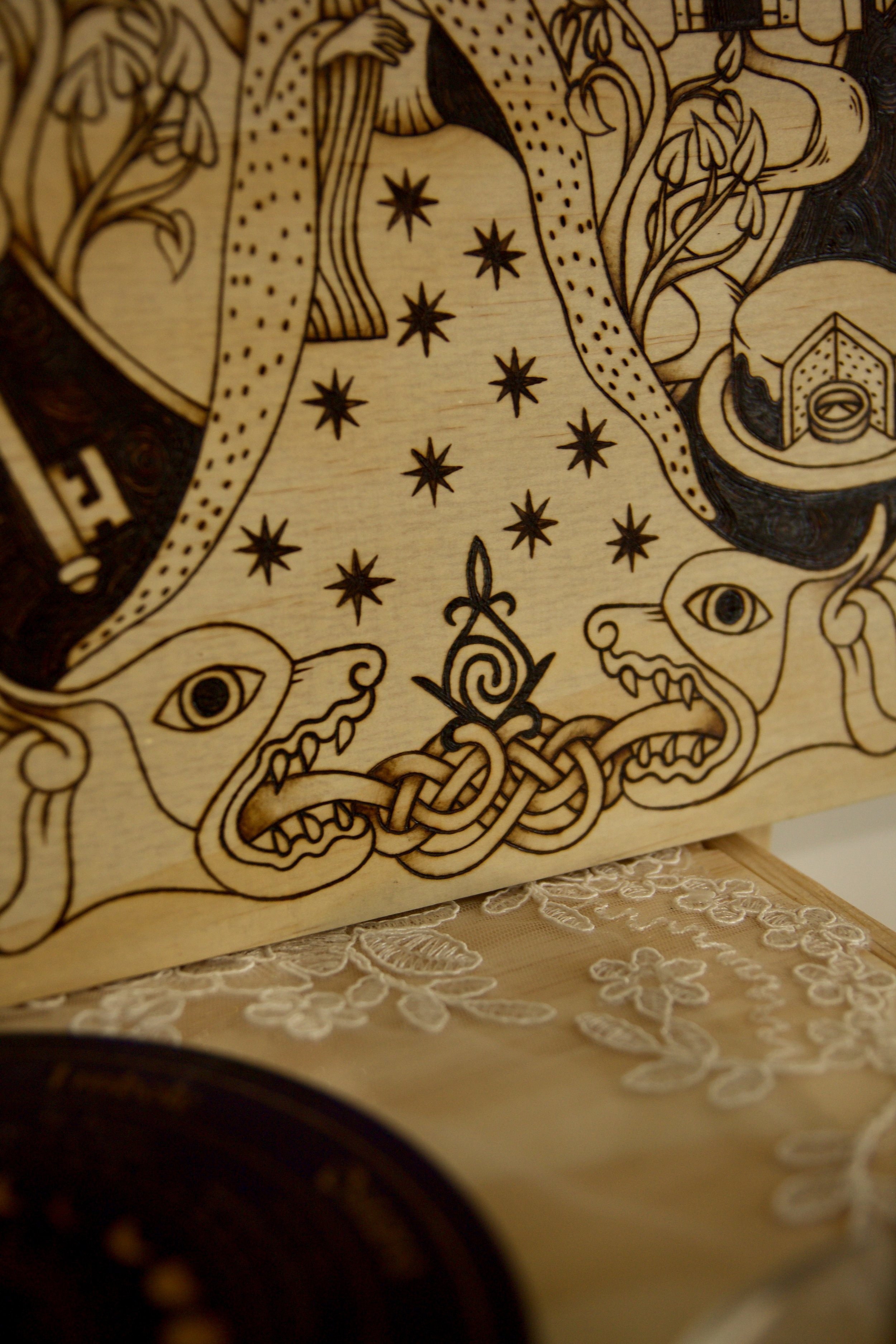 Détail d'un noeud celtique de lion sur un tableau carré en bois pyrogravé à la main représentant une illustration du conte Peau d’Âne inspirée du style des enluminures médiévales.