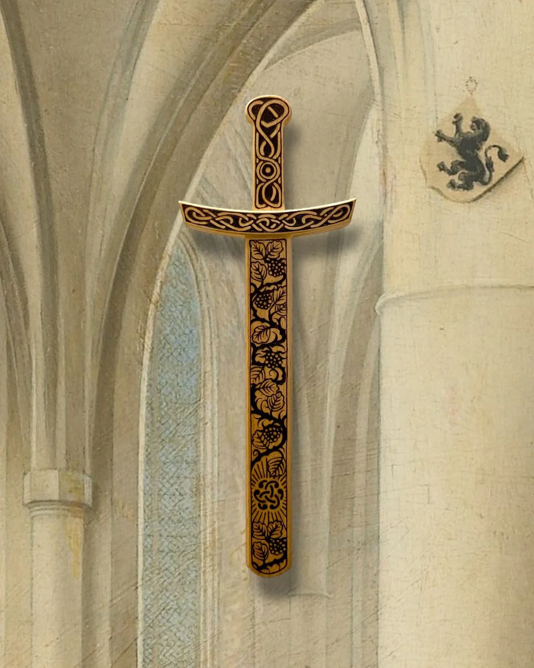 Épée décorative en bois clair posée sur un mur d'église ancienne entièrement pyrogravée à la main avec des motifs d'entrelacs celtiques, nœuds mystiques et inspirations médiévales.