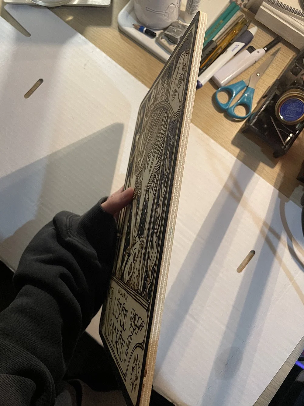 Vue de la tranche d'une pyrogravure artisanale faite main représentant l'épée sacrée Excalibur dans un style mystique et celtique, entourés de petites scènes et autres motifs folkloriques.
