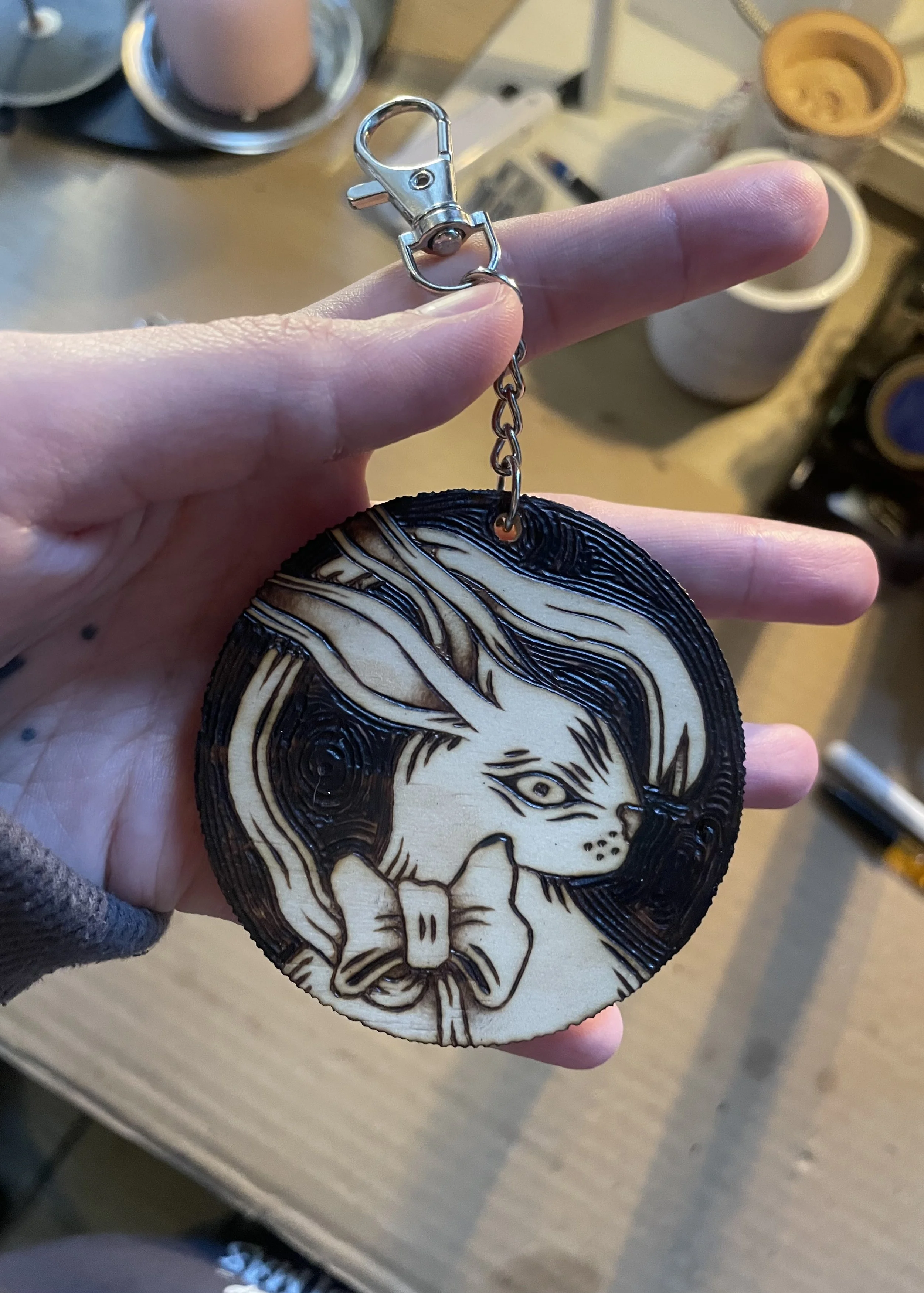 Porte-clé en bois artisanal pyrogravé à la main représentant un petit lapin mignon portant un nœud girly dans un atelier d'artiste.