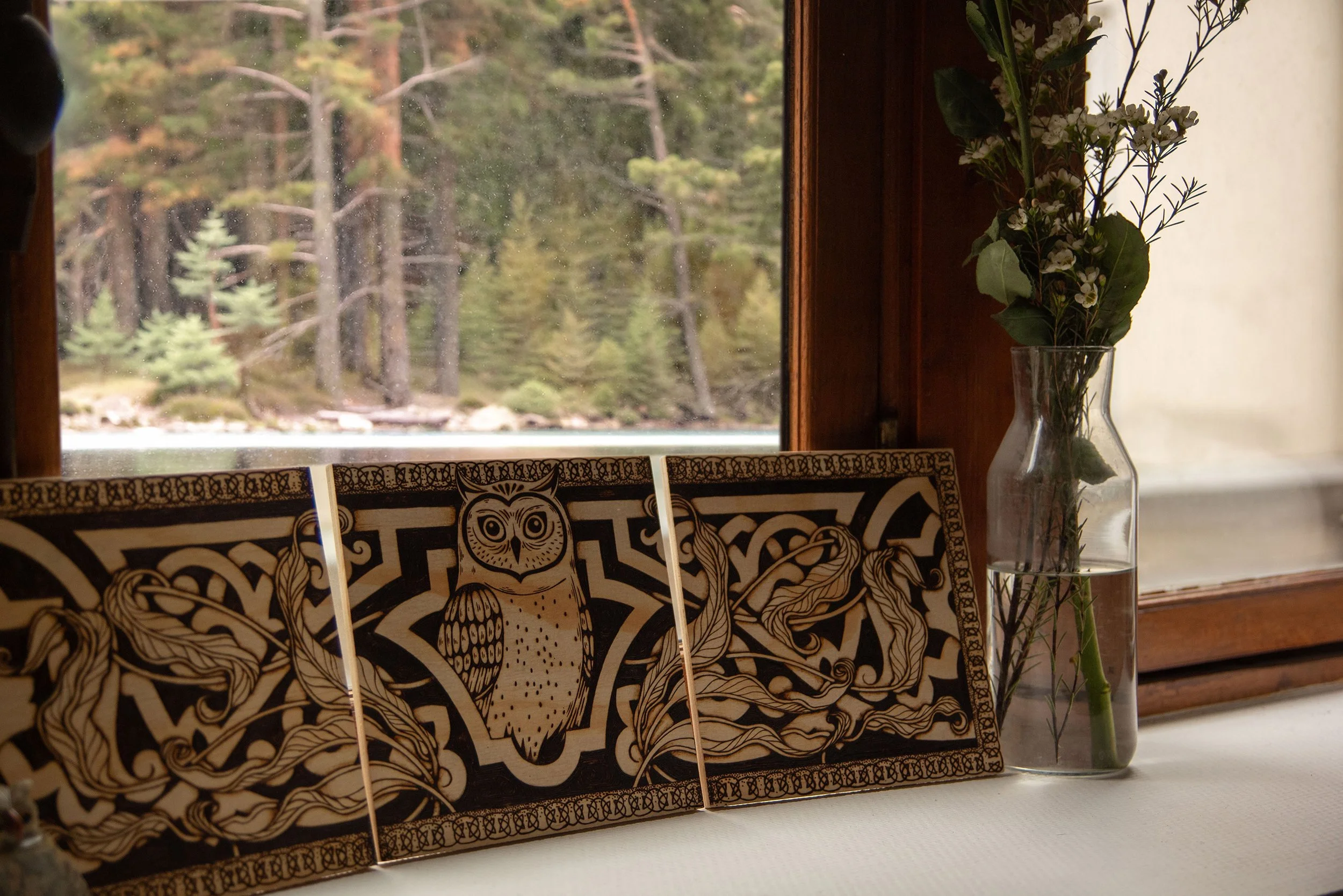 Triptyque mural en bois composé de trois panneaux pyrogravés à la main, représentant un hibou mystique entouré d'ornements et de motifs végétaux dans un décor de forêt mystique..