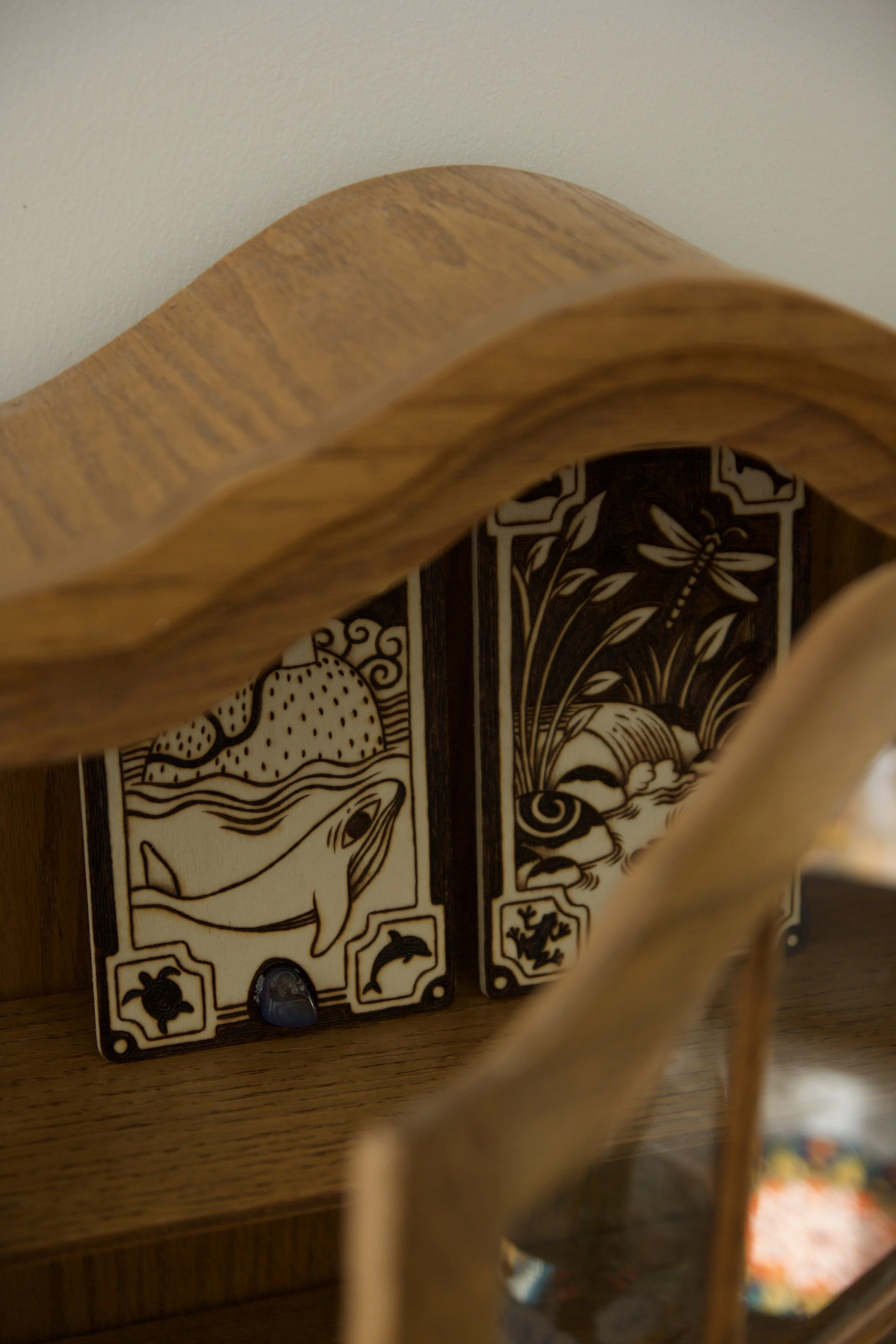 Deux plaques en bois gravée à la main sur les thèmes de la mer et de la rivière, serties de deux pierres semi précieuses dans une bibliothèque ancienne.