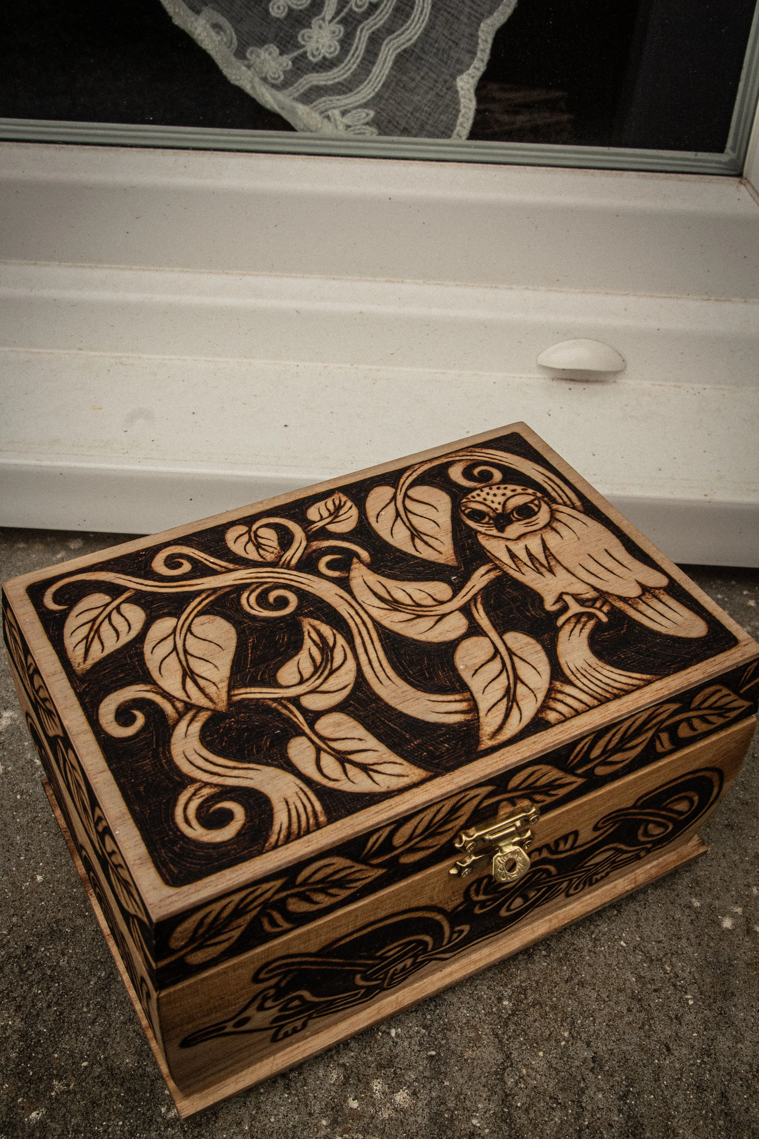Couvercle d'une boîte en bois pyrogravée à la main représentant un hibou entouré de branches entrelacées et de motifs celtiques.