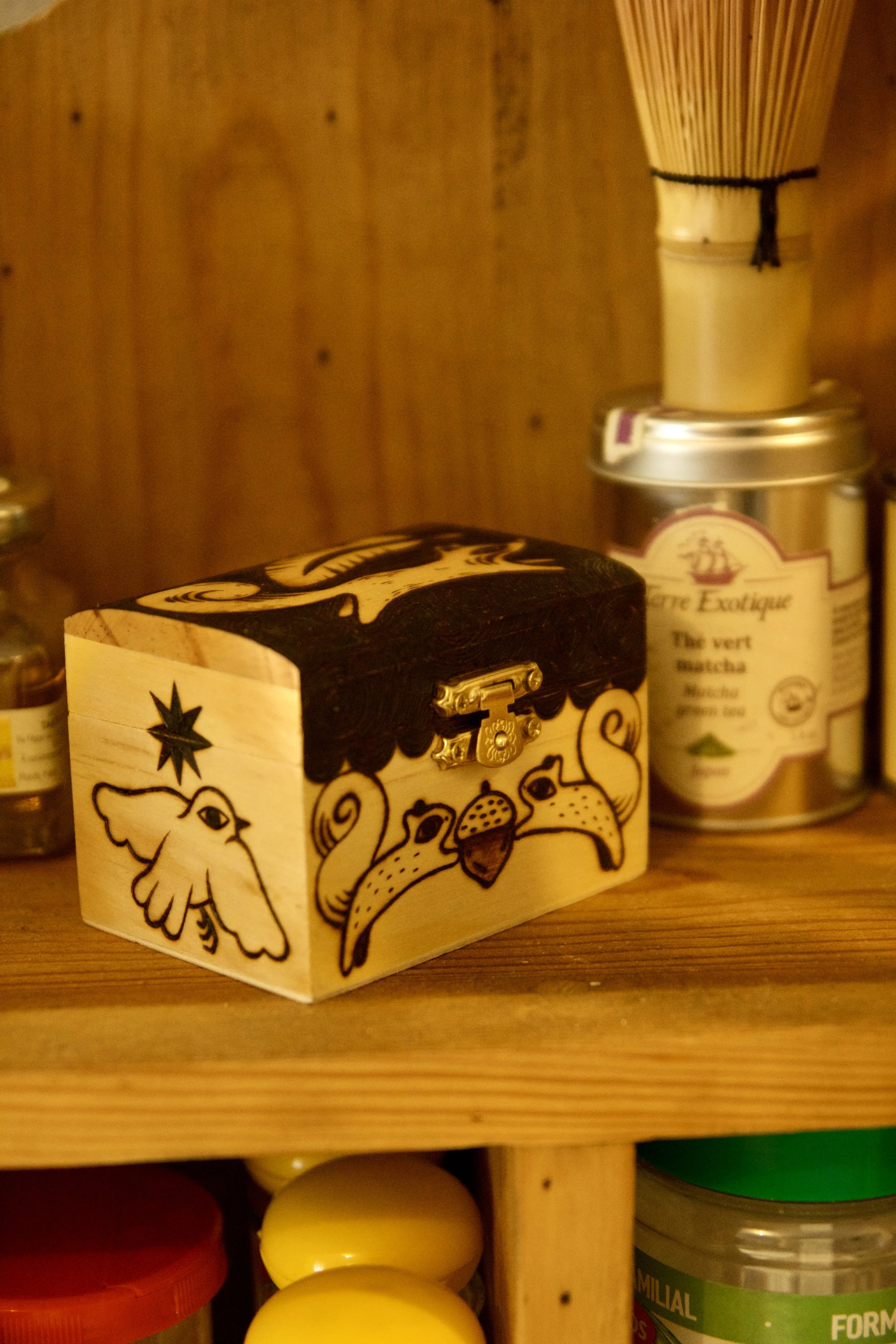 Petite boîte en bois mystique pyrogravée main, illustrée avec des écureuils, un renard, un oiseau et les phases de la lune dans un décor de cuisine ancienne.