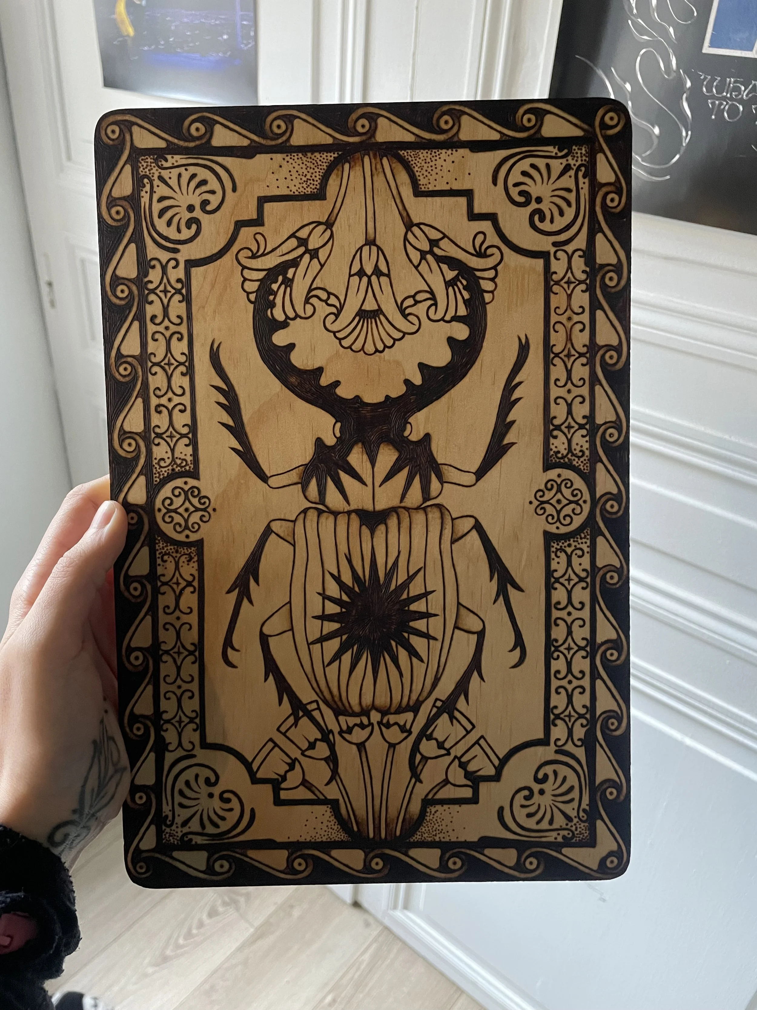 Plaque en bois artisanale pyrogravée à la main représentant un scarabée sacré entouré de symboles anciens et de motifs ésotériques géométriques.