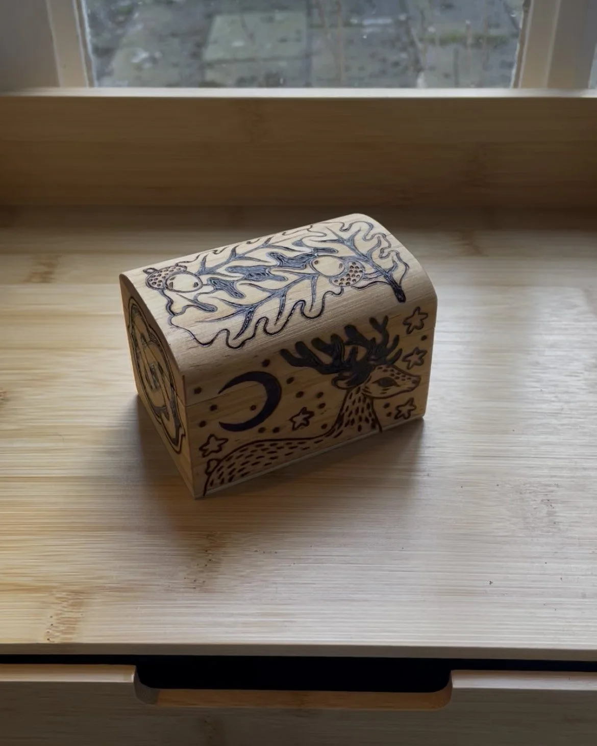 Petite boîte mystique vue de face en bois pyrogravée à la main avec un motif de cerf majestueux, des nœuds celtiques et des feuilles d'automne.