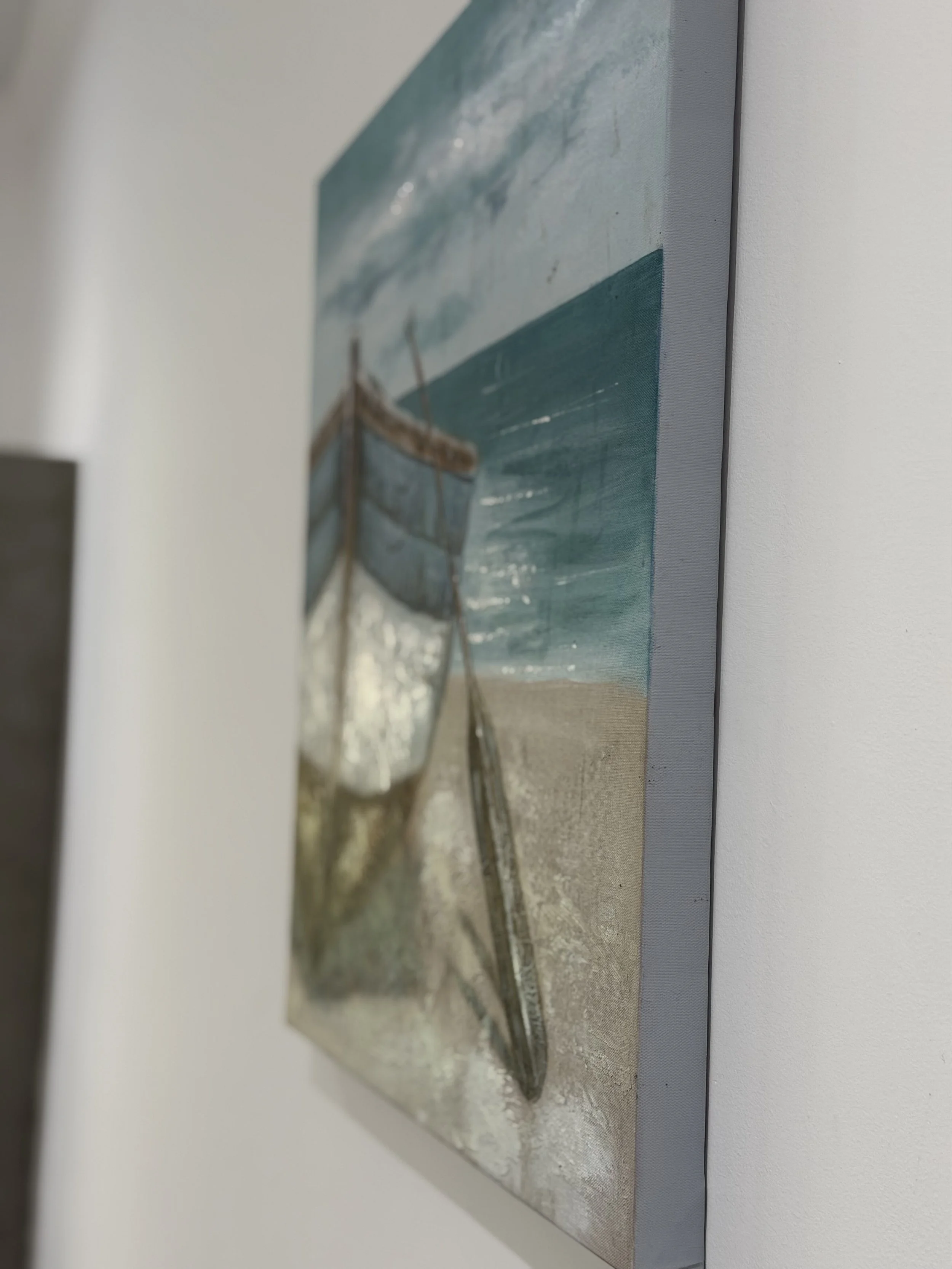 Close-up photograph of a textured surface resembling a seascape painting with water, a boat, and a body of land, hanging on a white wall.