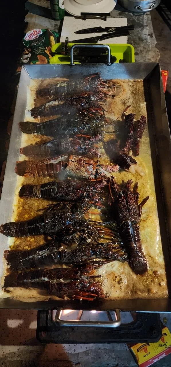Several cooked lobsters on a baking sheet in a kitchen