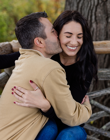 A couple hugging outdoors, smiling and enjoying each other.