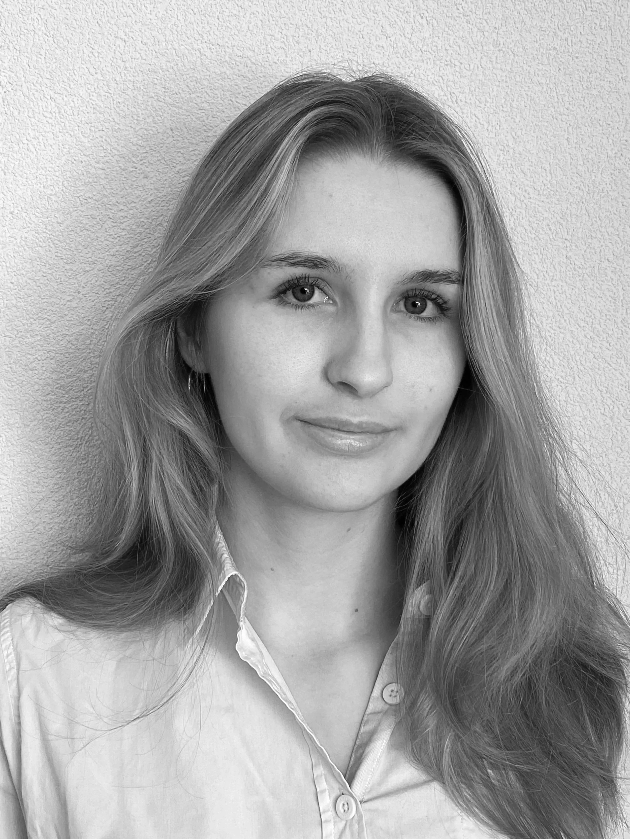 Portrait en noir et blanc d'une femme à longue chevelure, souriante légèrement, portant une chemise.
