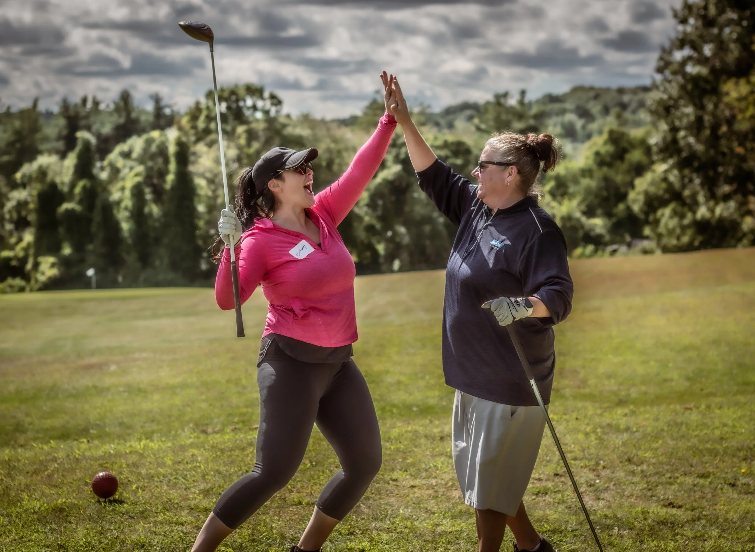 Lunenburg Business Association members high fiving at a charity golf tournament supporting the Lunenburg Teen Center, celebrating teamwork, community impact, and local business support.