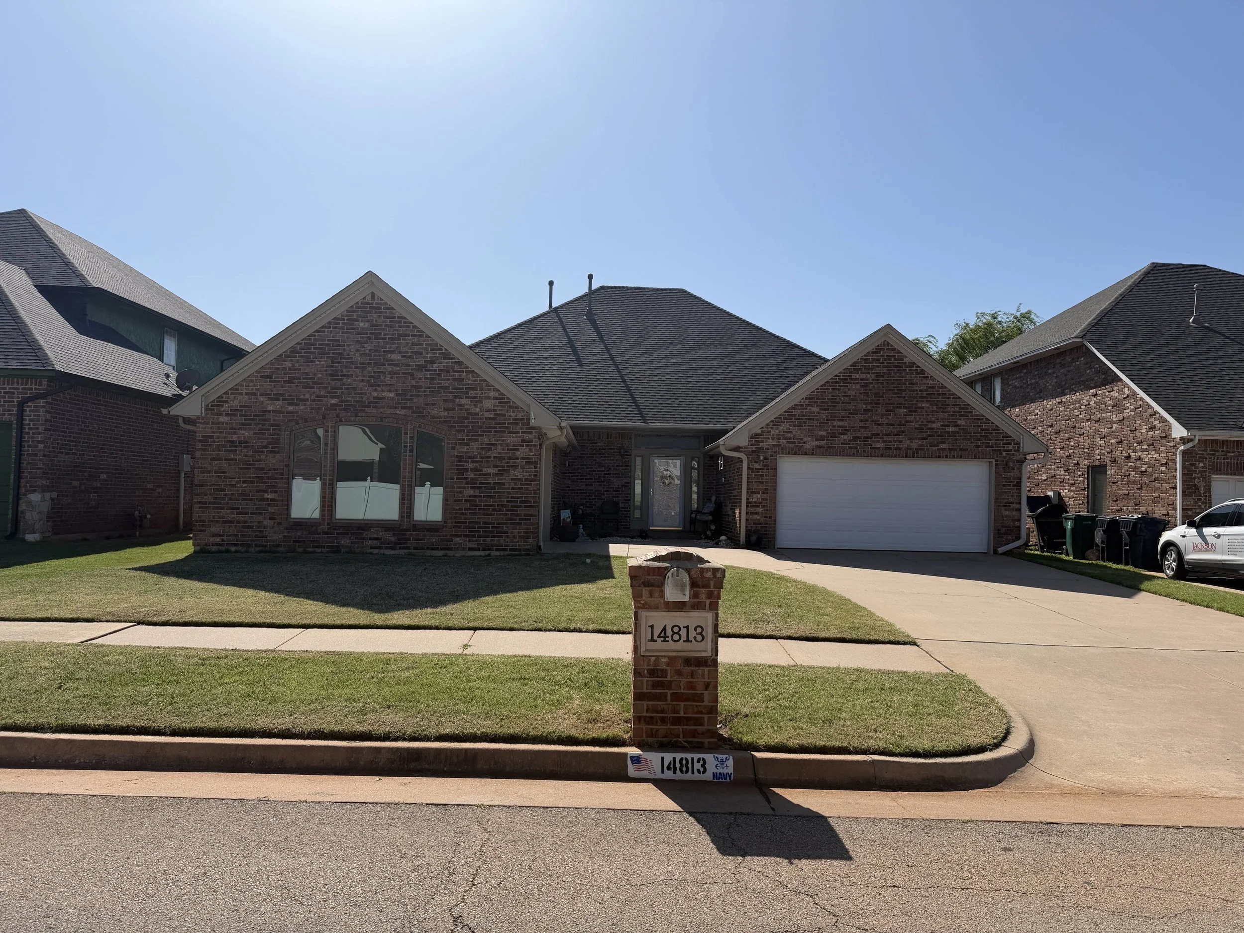 A suburban house with a brick exterior, a new gabled roof, and a white garage door.